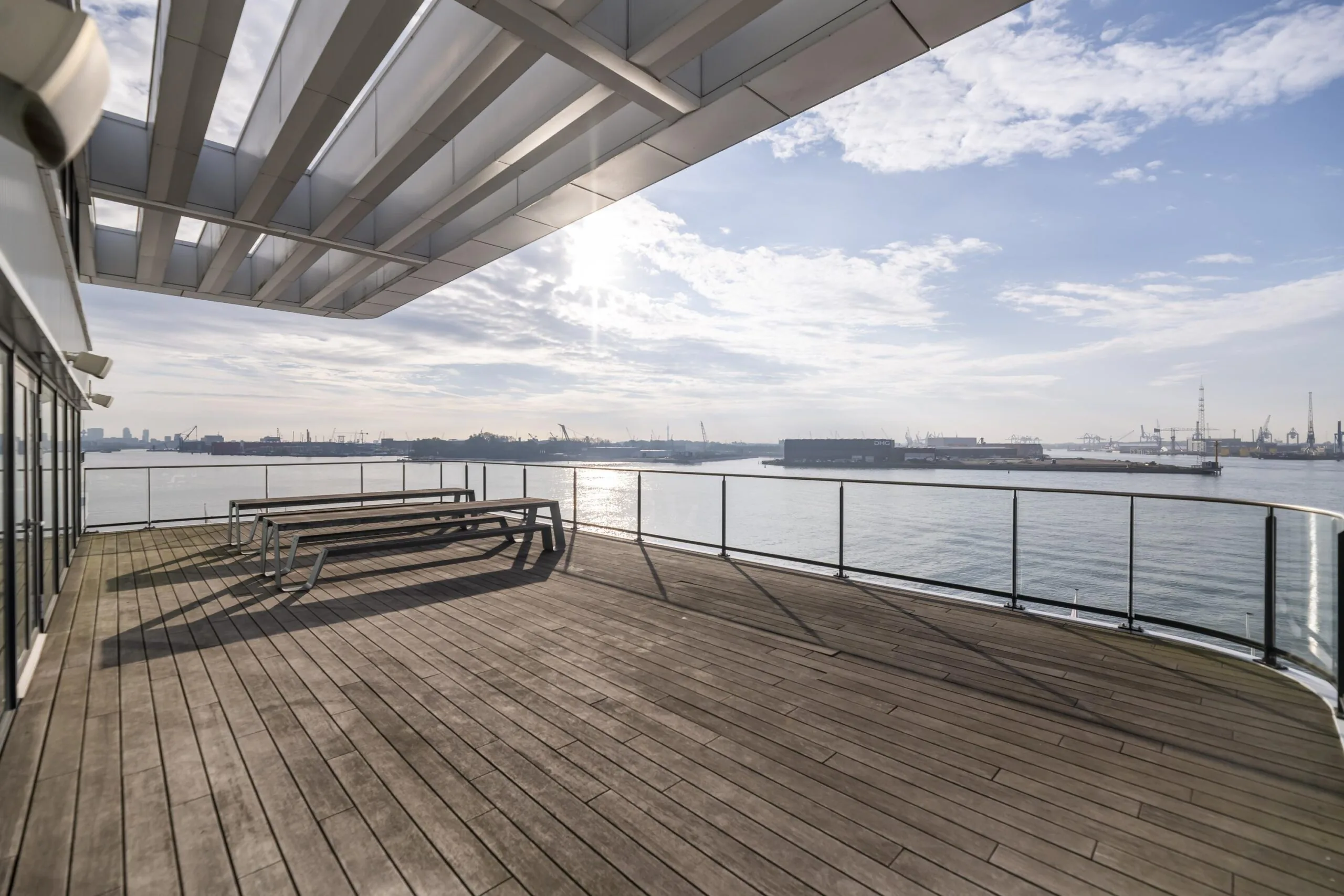 Ruim houten dakterras met picknicktafels en uitzicht op het water en de haven aan de Havenstraat.