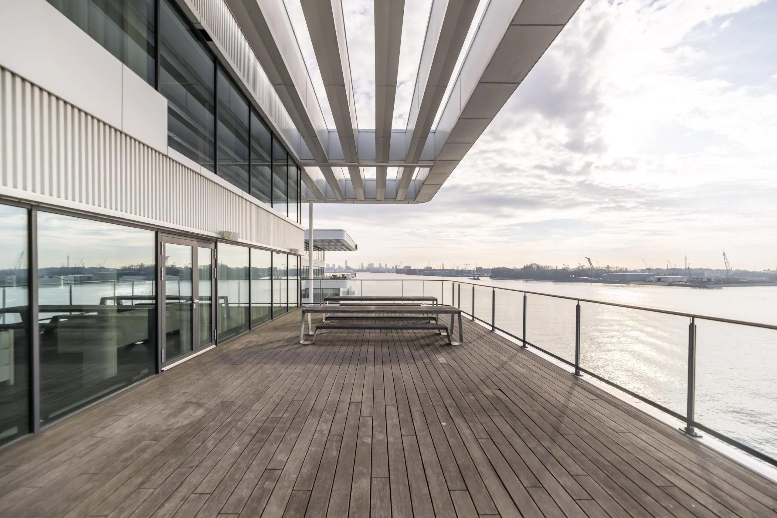 Modern dakterras aan de Havenstraat met houten vlonder, glazen balustrade en uitzicht over het water en de haven.