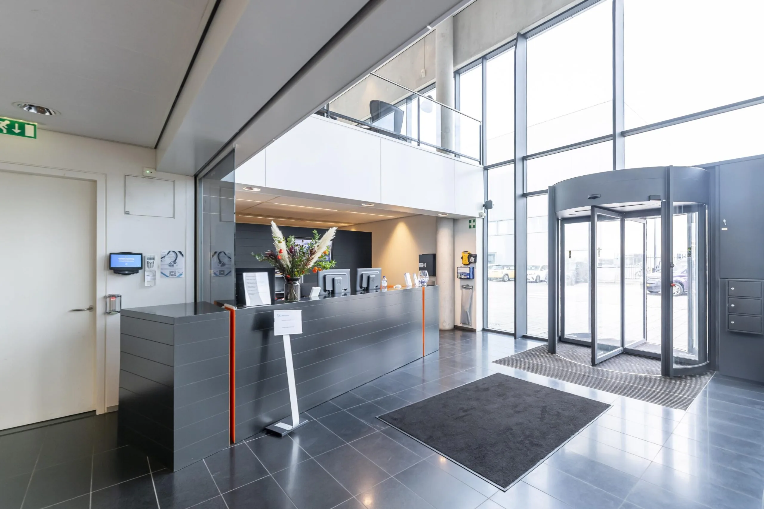 Moderne ontvangsthal met balie, draaideur en grote glazen gevel aan de Havenstraat.