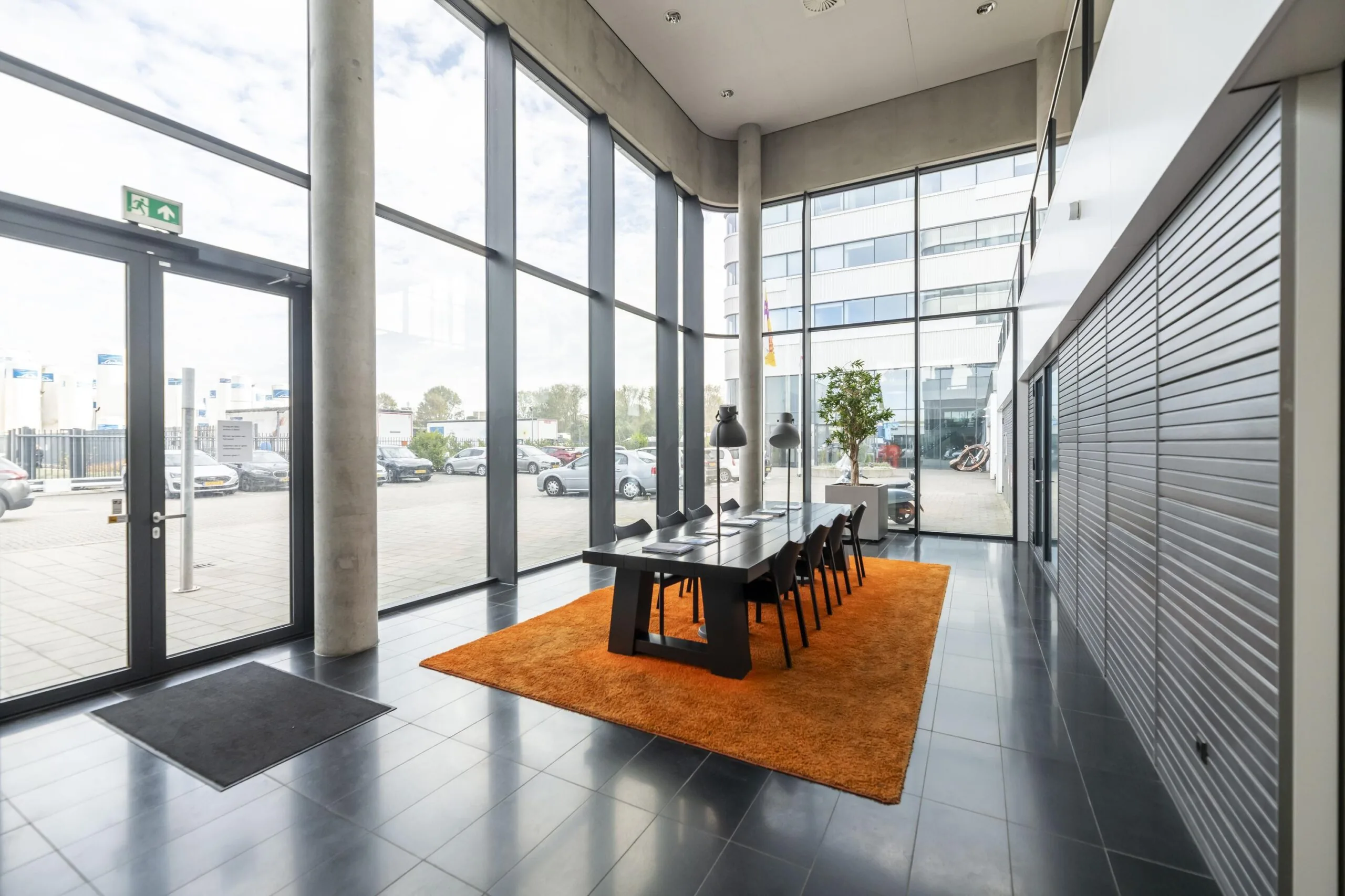 Moderne vergaderruimte aan de Havenstraat met hoge ramen, een lange tafel en een oranje vloerkleed.