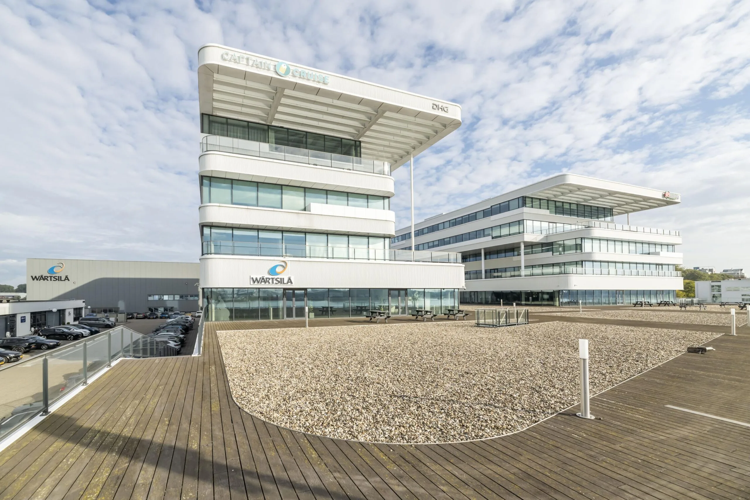 Modern bedrijfsgebouw van Wärtsilä aan de Havenstraat met glazen gevels en ruim houten terras op de voorgrond.