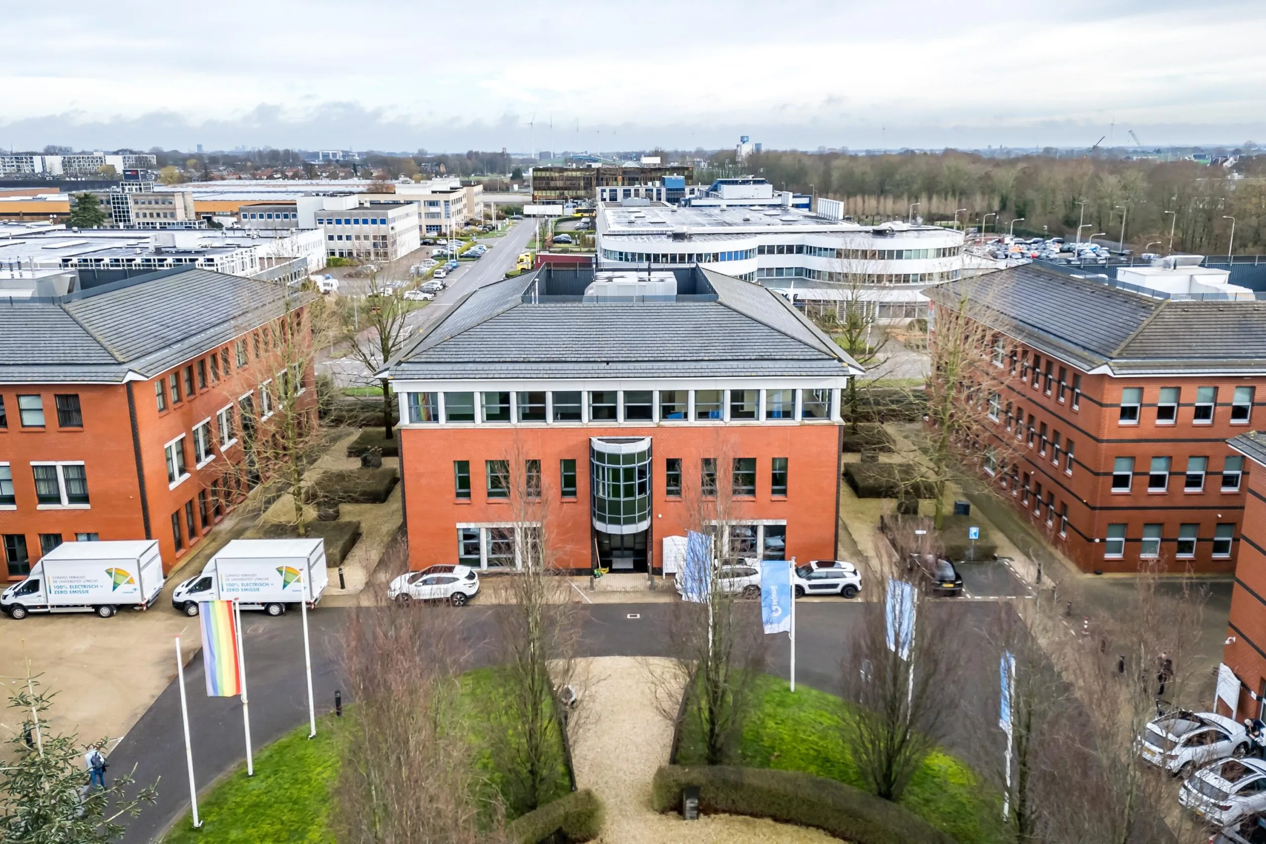 Luchtfoto van een modern kantoorgebouw aan de Lange Dreef, omringd door vergelijkbare rode bakstenen panden en geparkeerde voertuigen.