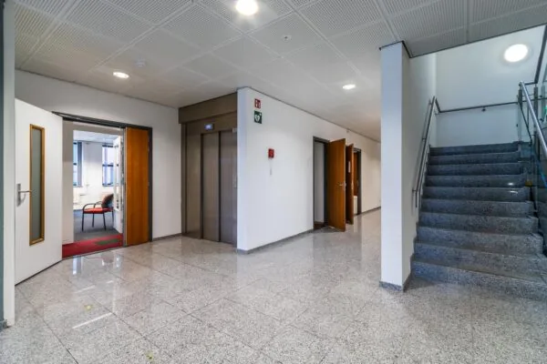 Moderne kantoorhal met lift, trap en meerdere openstaande deuren aan de Lange Dreef.
