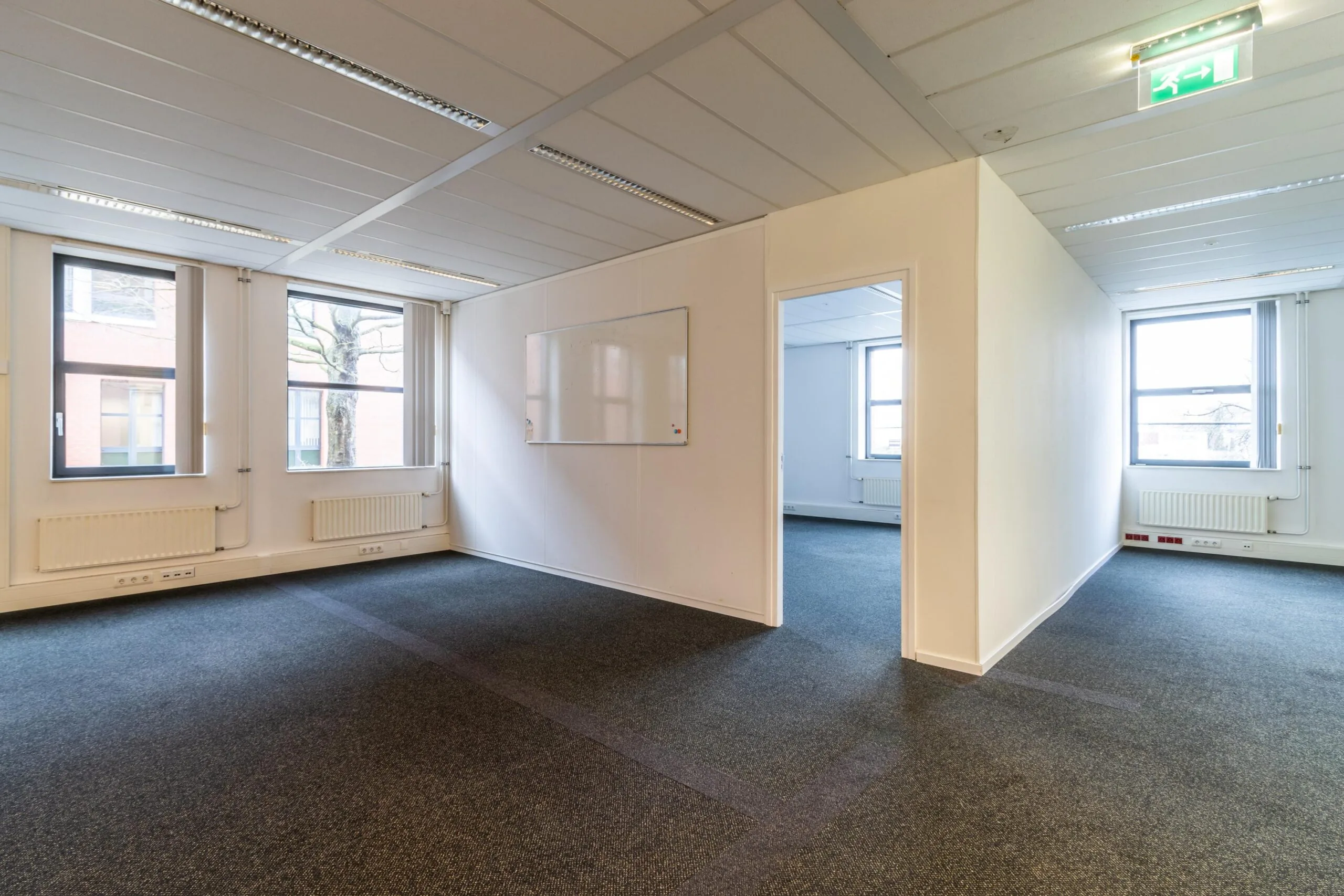 Licht en leeg kantoorpand aan de Lange Dreef met meerdere ruimtes, grote ramen en een whiteboard aan de muur.
