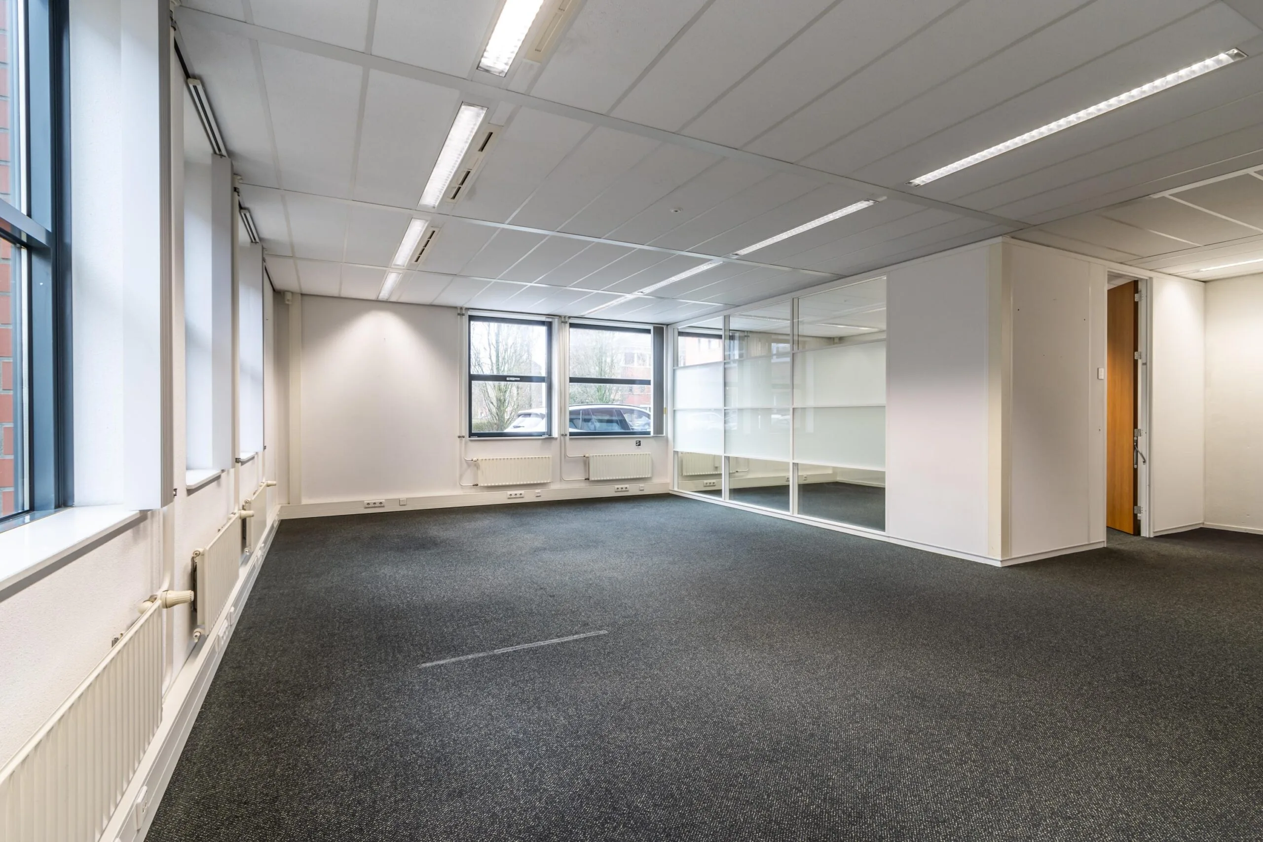 Licht, leeg kantoor aan de Lange Dreef met grote ramen en glazen scheidingswand.