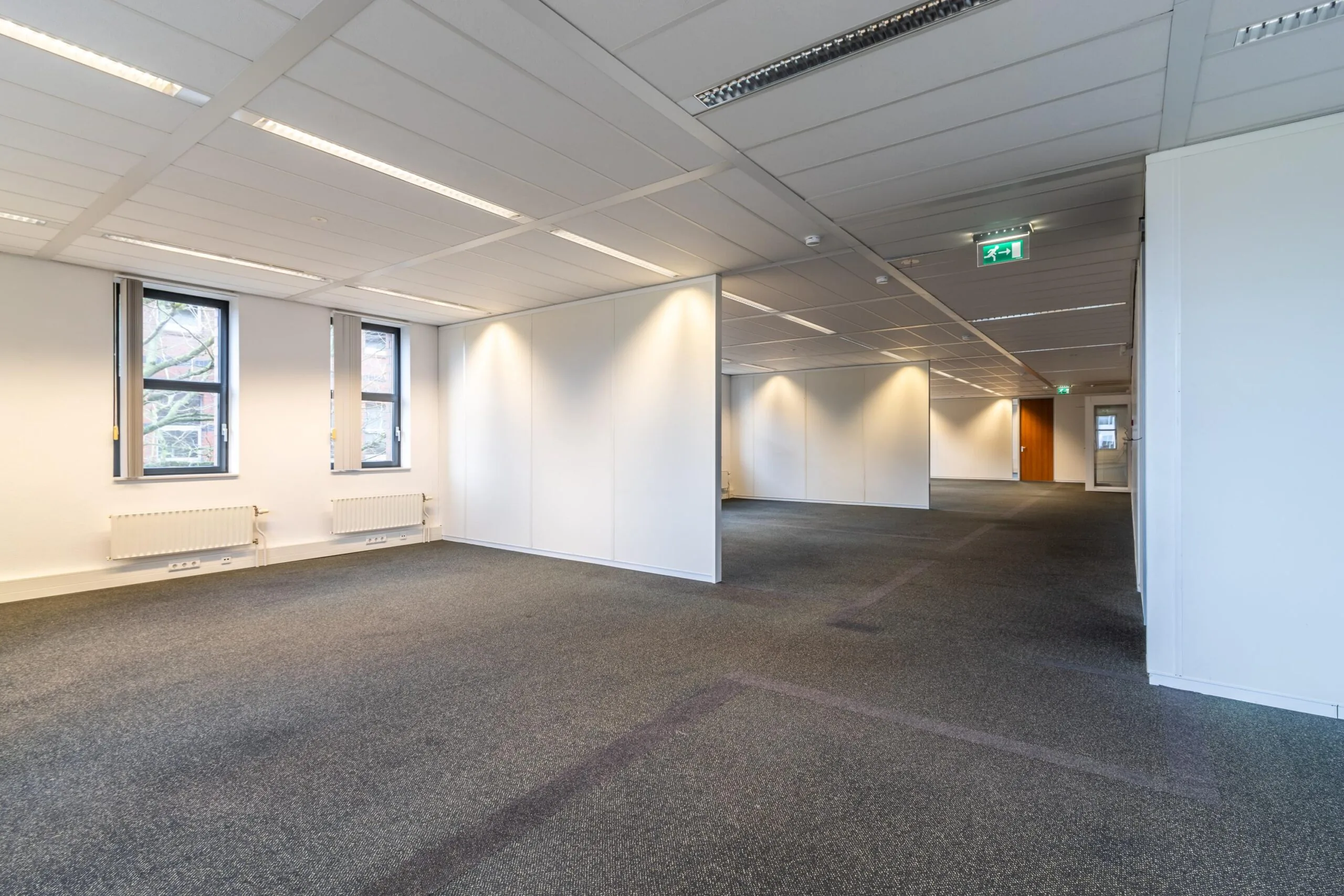 Leeg kantoorpand aan de Lange Dreef met tapijtvloer, systeemplafond en witte scheidingswanden.