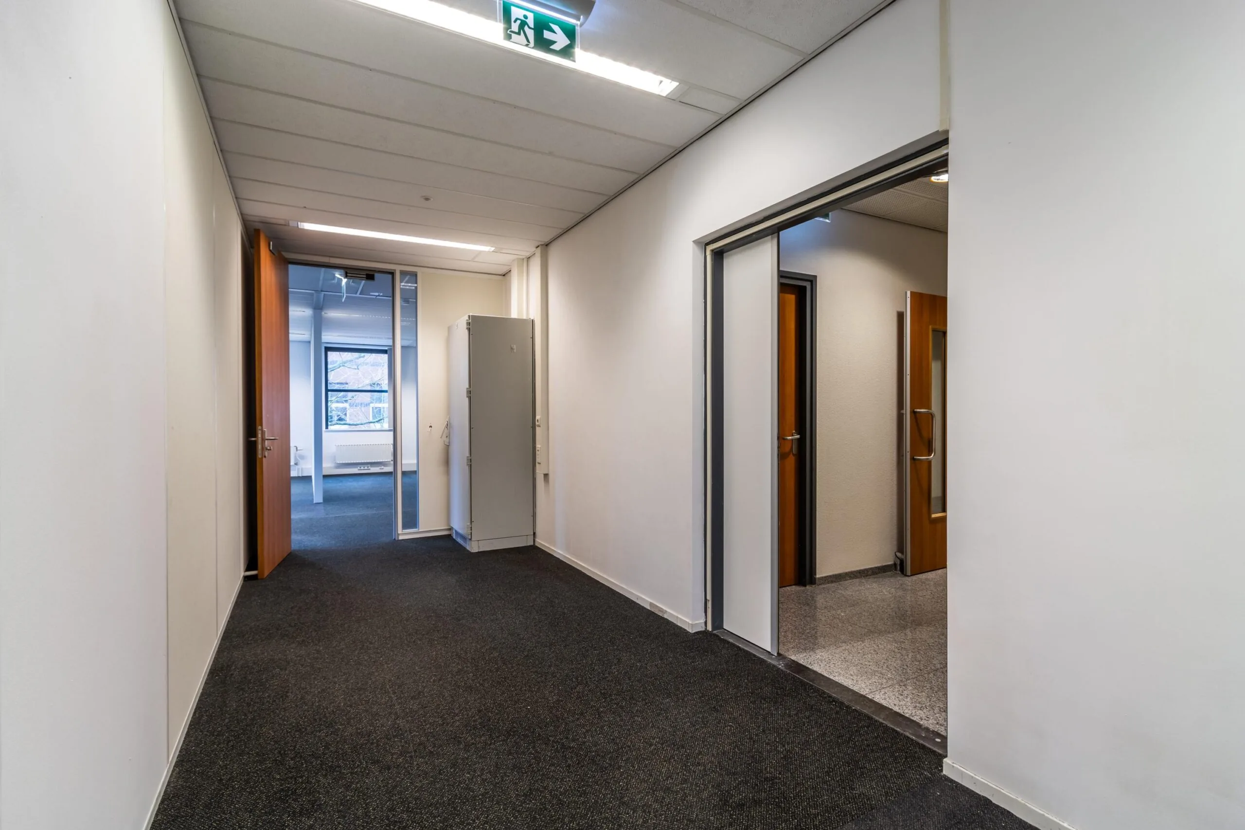 Hal met tapijtvloer en meerdere deuren in een kantoorpand aan de Lange Dreef.