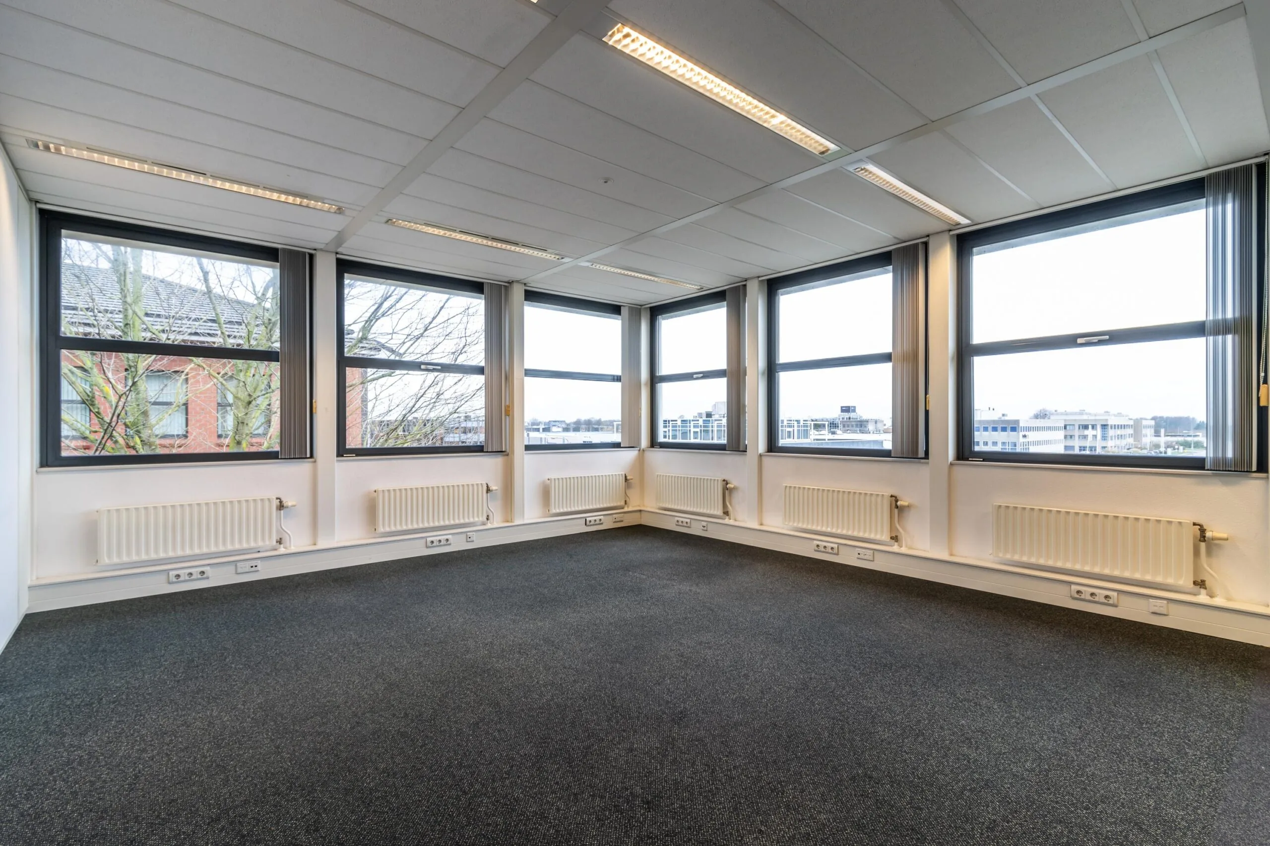 Lichte, leegstaande kantoorruimte aan de Lange Dreef met grote ramen en uitzicht op omliggende gebouwen.