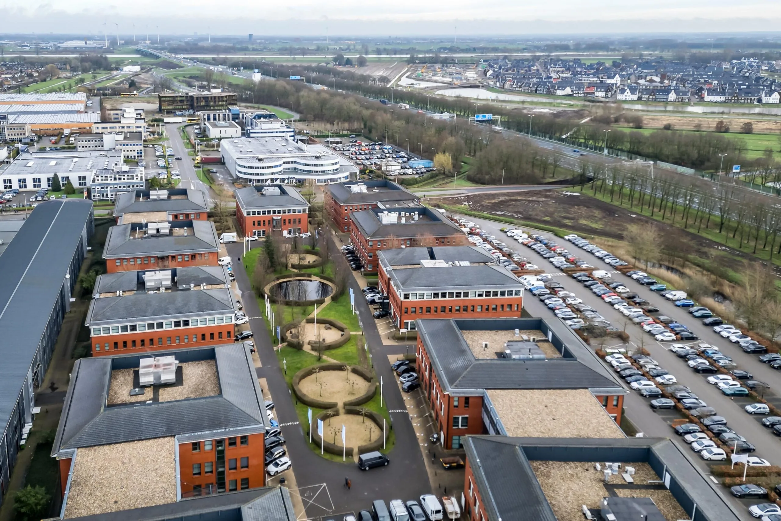 Luchtfoto van het kantorenterrein Lange Dreef met rode bakstenen kantoorgebouwen, parkeerplaatsen en groenvoorzieningen.