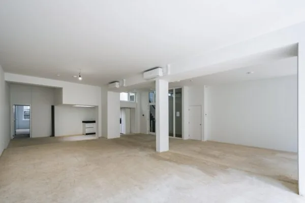 Ruime, lichte commerciële ruimte op de Damrak met witte muren, steunpilaren en open indeling.