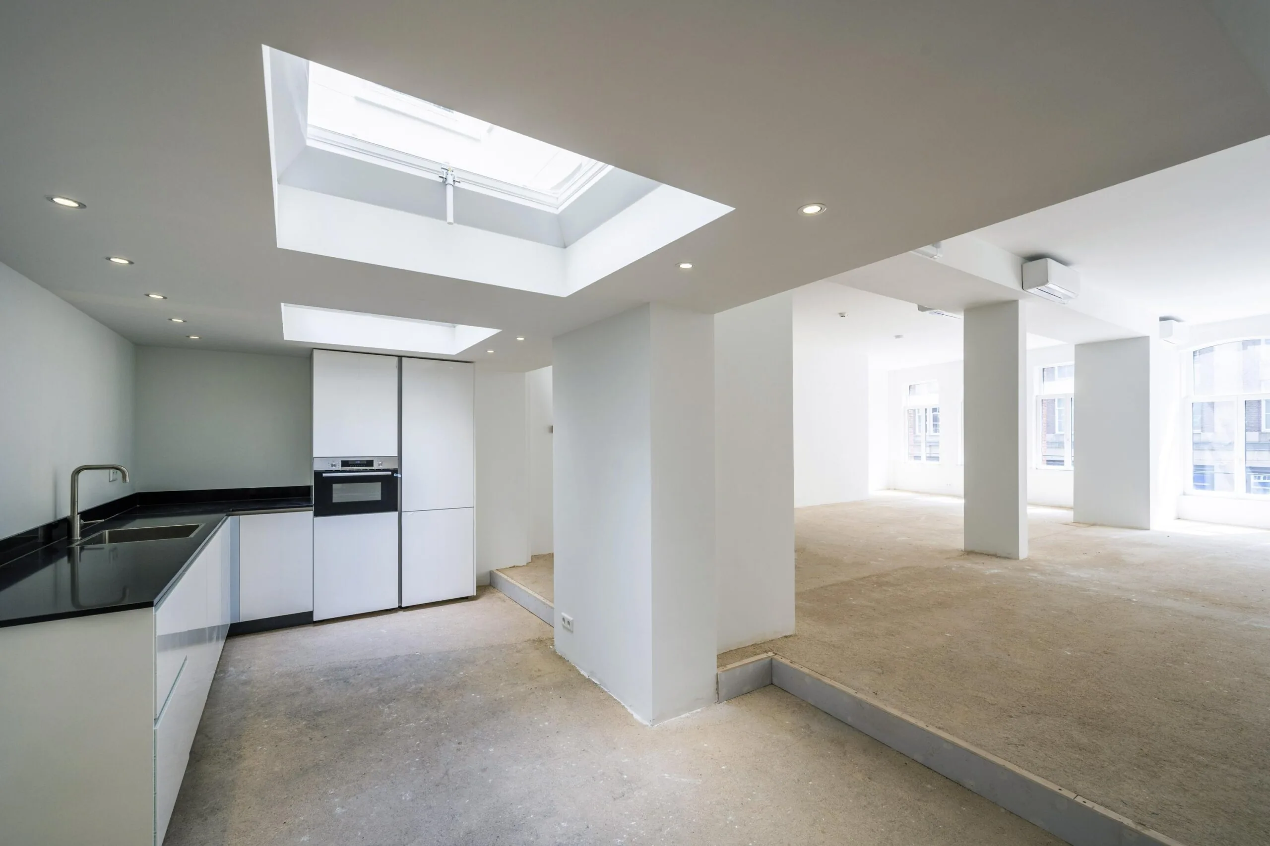 Licht en open interieur van een gerenoveerd appartement aan het Damrak met moderne keuken en grote ramen.