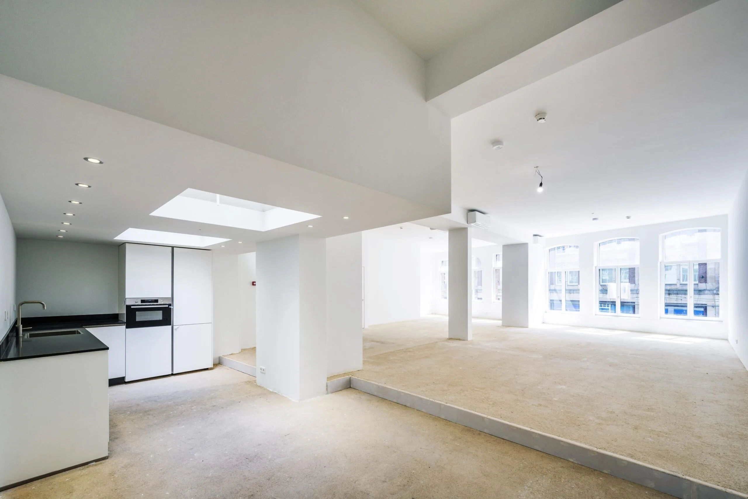 Ruime, lichte casco woonruimte aan het Damrak met open keuken en grote ramen.