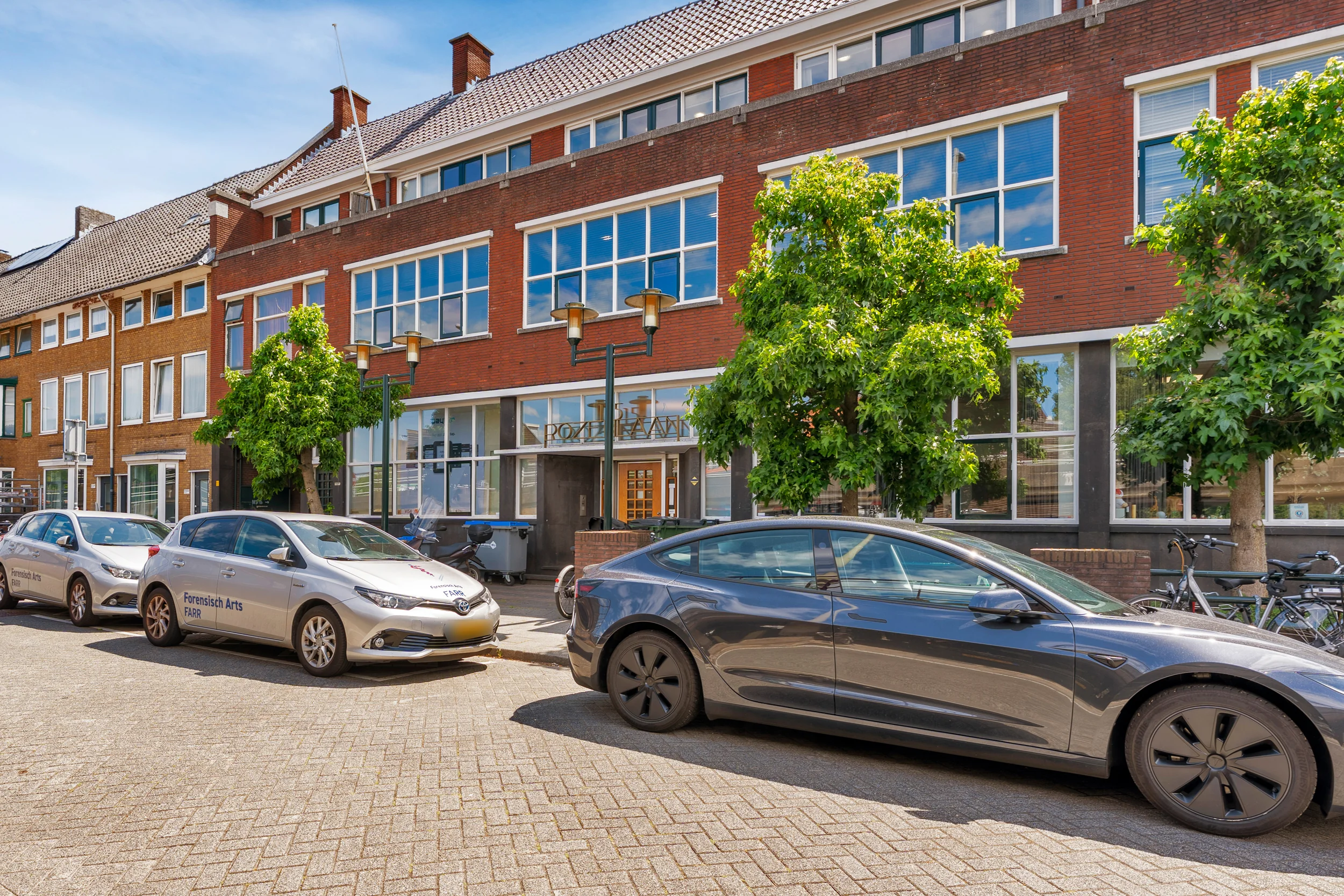 Street view of the Rozenlaan building with parked cars and trees in front.