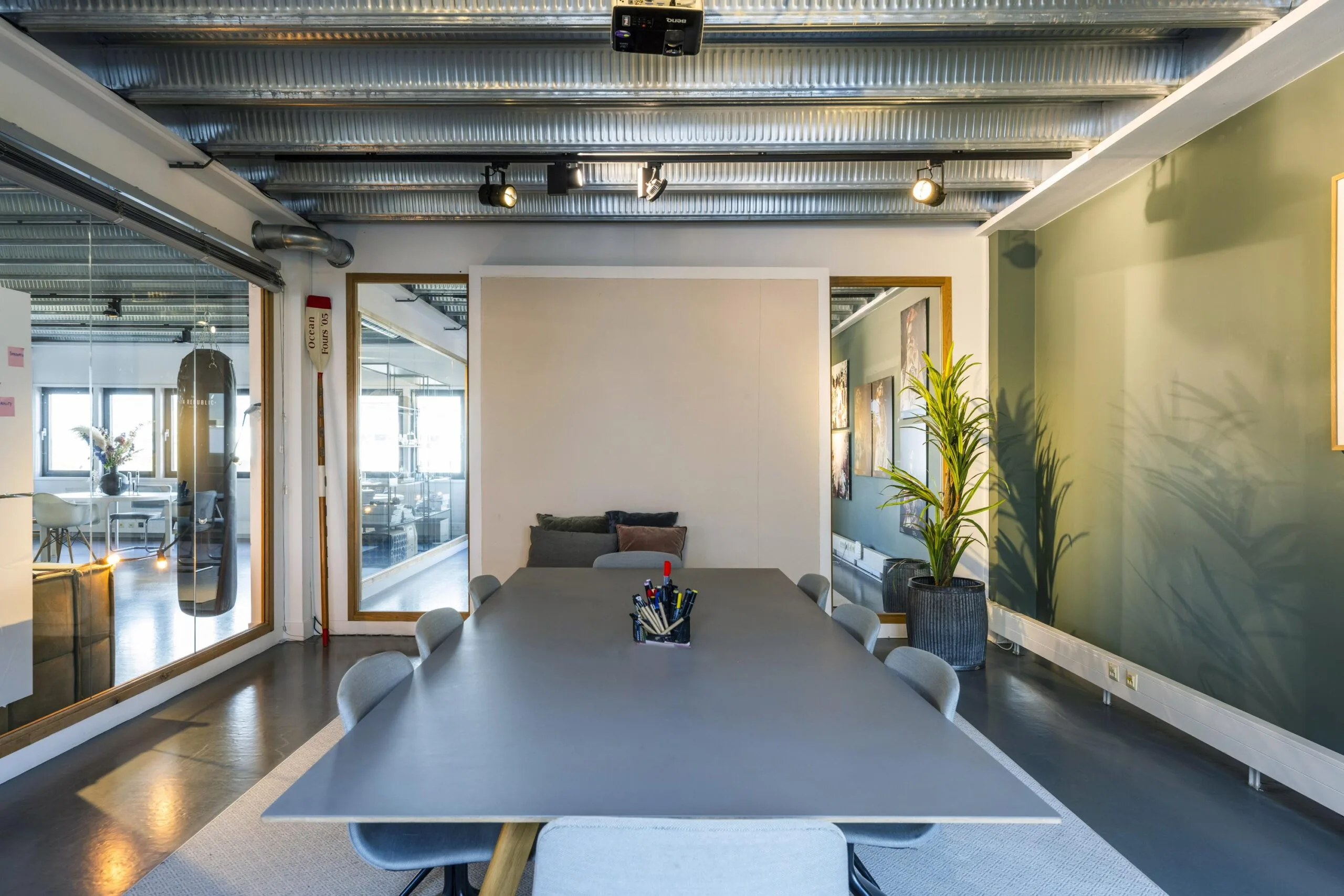 Modern meeting room on Helicopterstraat with a large table, office chairs, and industrial ceiling design.