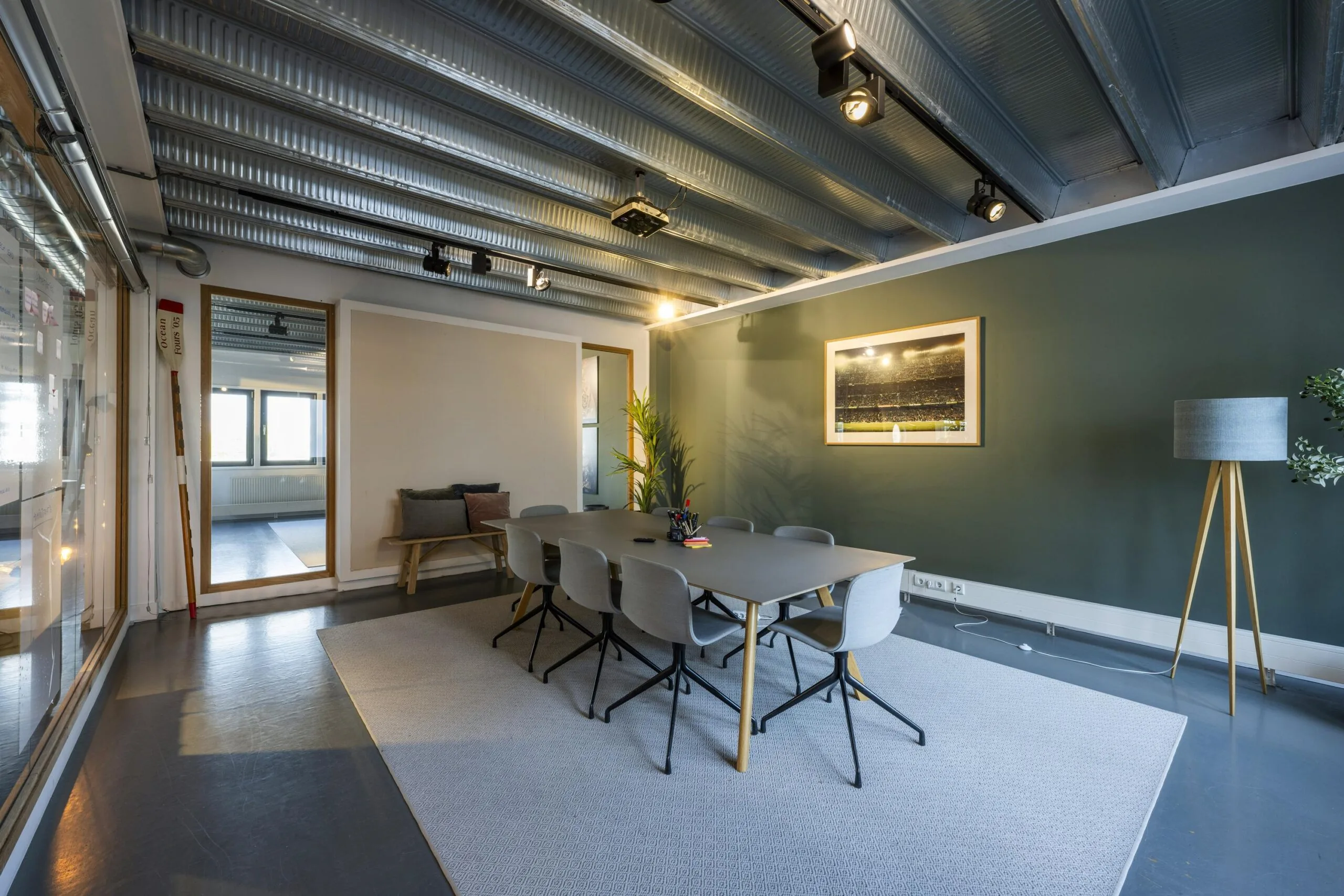 Modern meeting room on Helicopterstraat with a large table, six chairs, and industrial ceiling design.