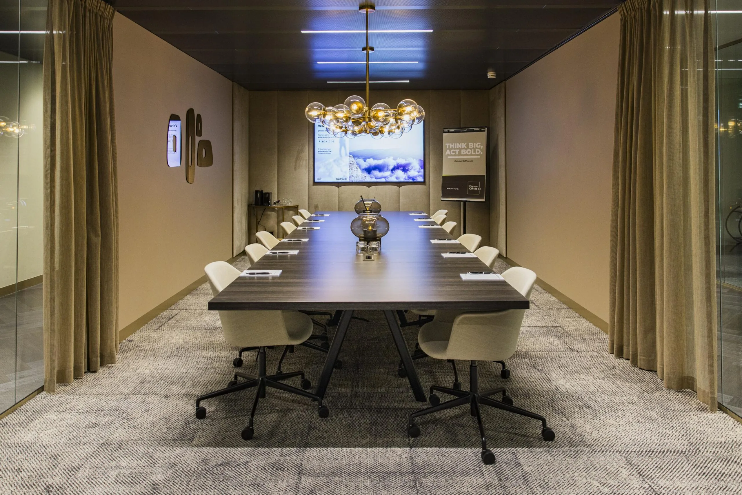 Modern conference room with a long wooden table, beige chairs, and a decorative chandelier.