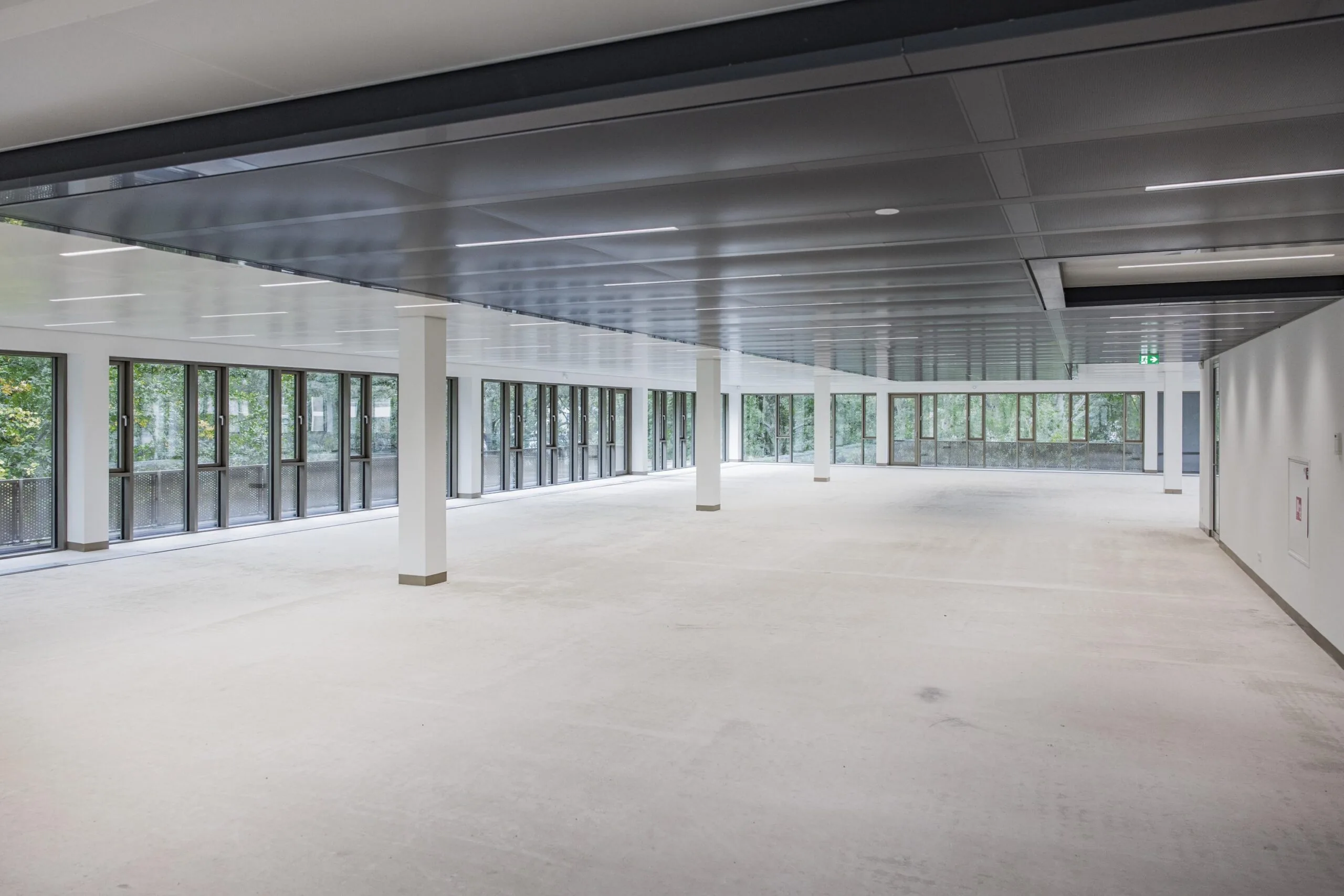 Spacious empty office floor with large windows and modern ceiling at Walborg 176.