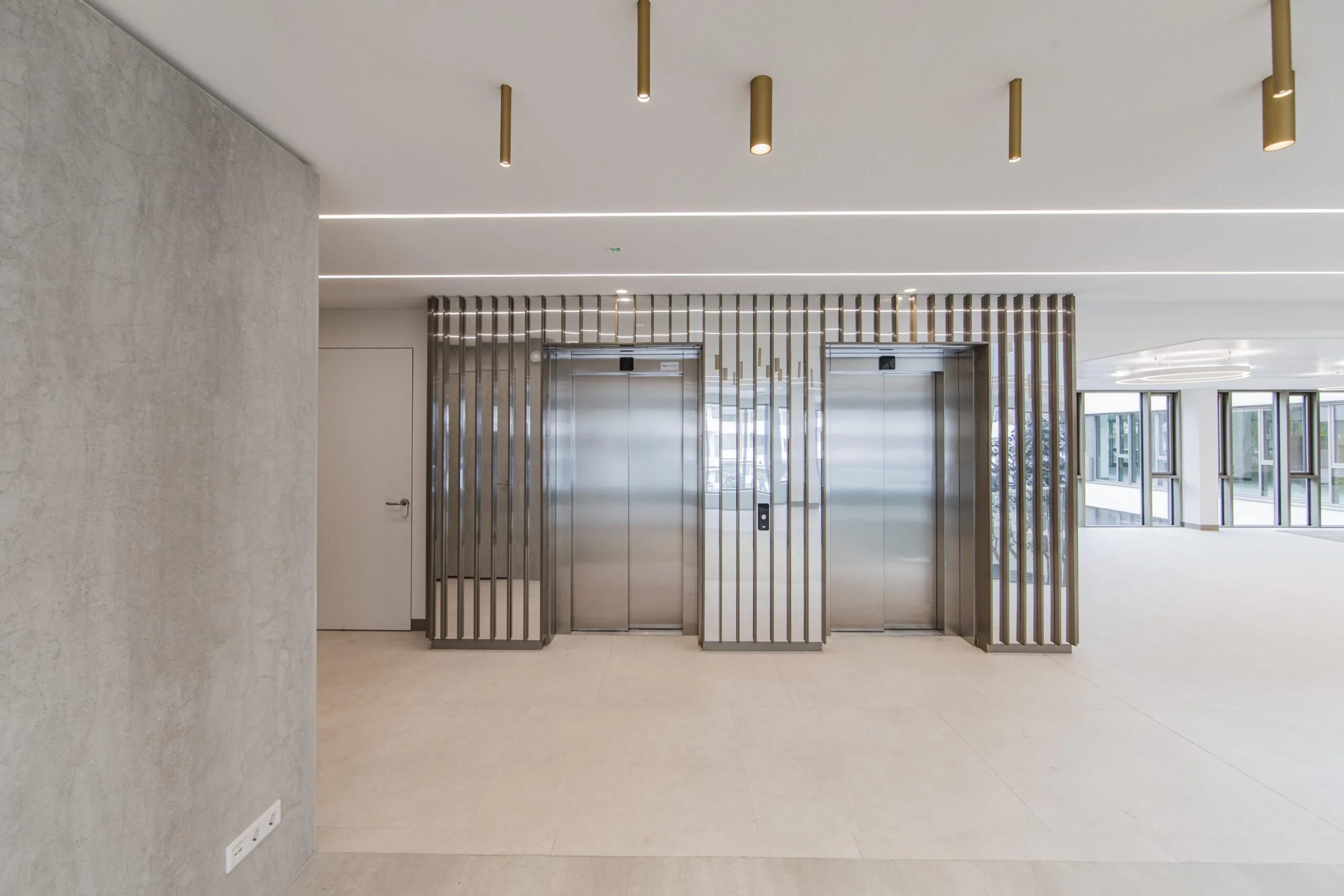 Modern lobby with two stainless steel elevators and gold ceiling lights in the Walborg building.