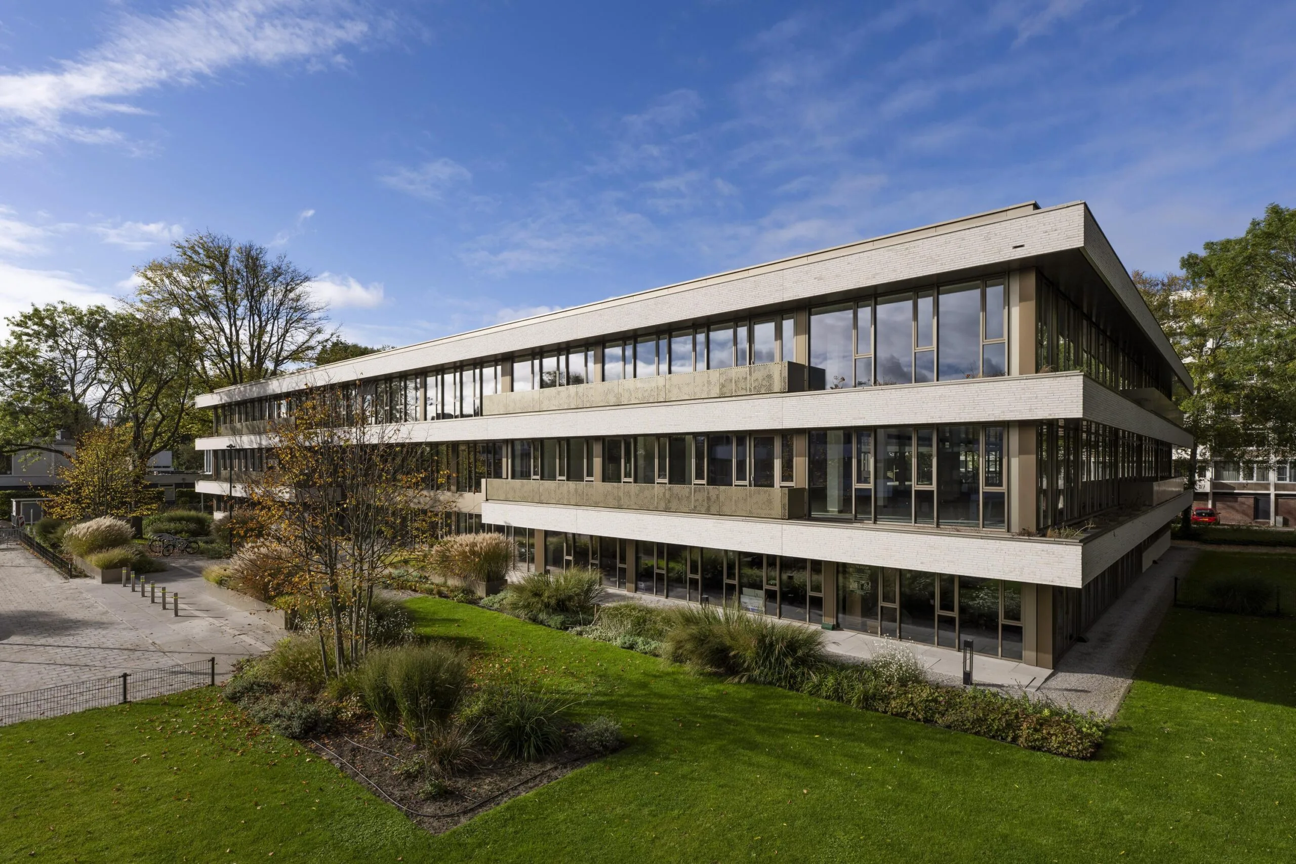 Modern three-story office building "Walborg" with large windows, surrounded by greenery and a landscaped garden.