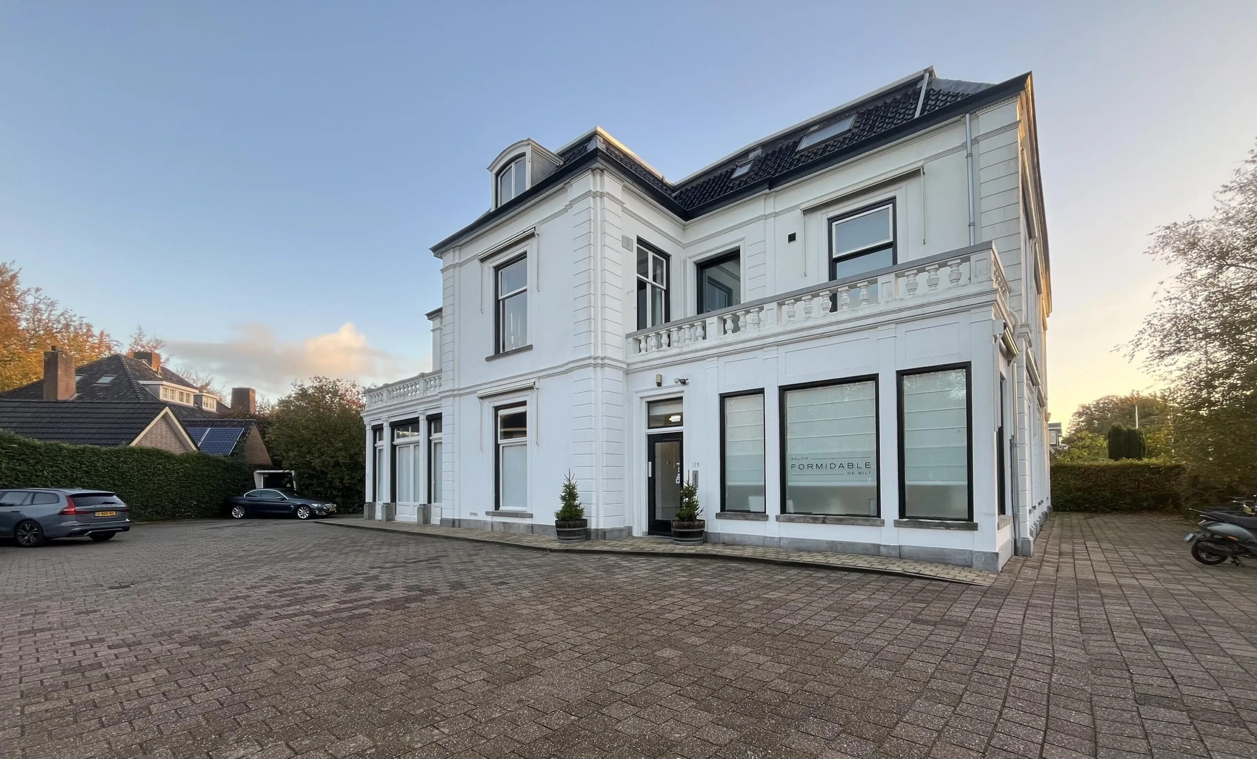 White historic-style building on Dorpsstraat with large windows and parked cars in front.