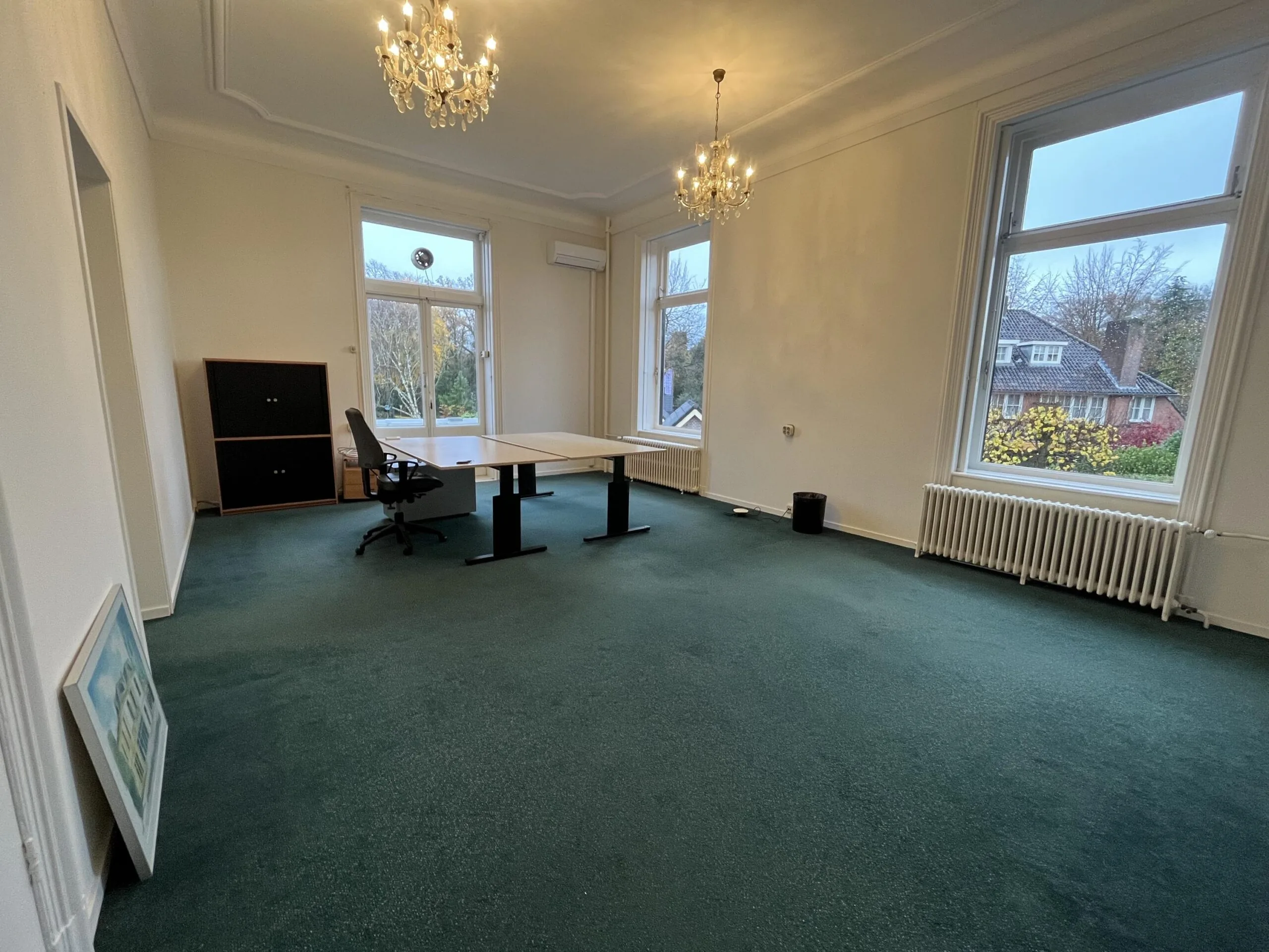 Spacious office room on Dorpsstraat with green carpet, large windows, and a single desk setup.