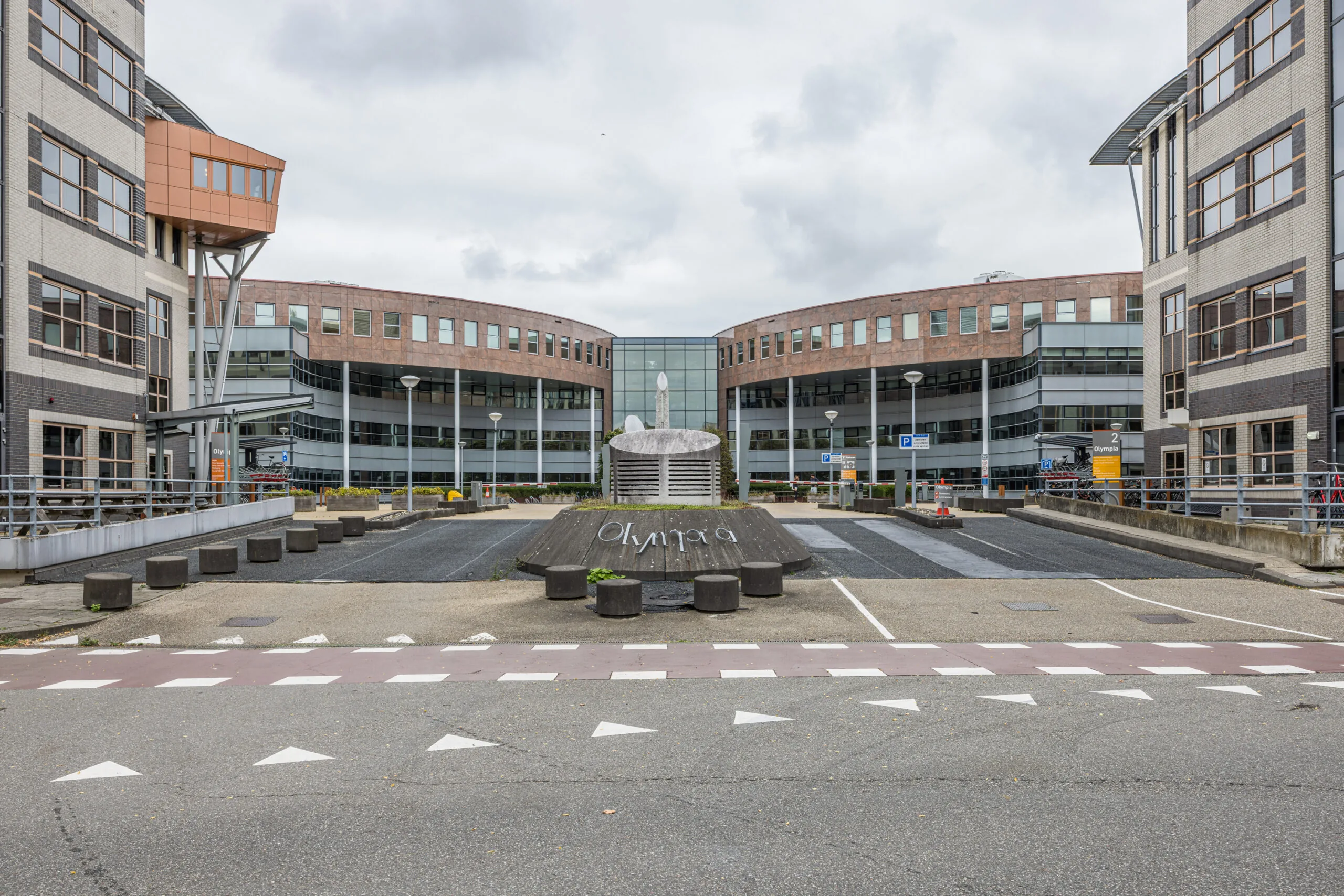 Modern office building complex named "Olympia" with a central sculpture and curved architecture.