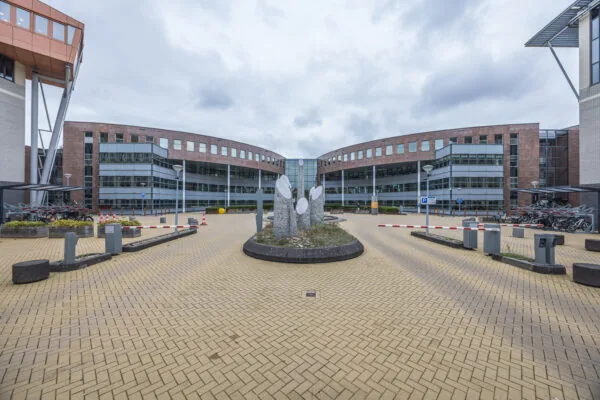 Modern office building of Olympia viewed from the entrance courtyard with a circular stone sculpture in the center.
