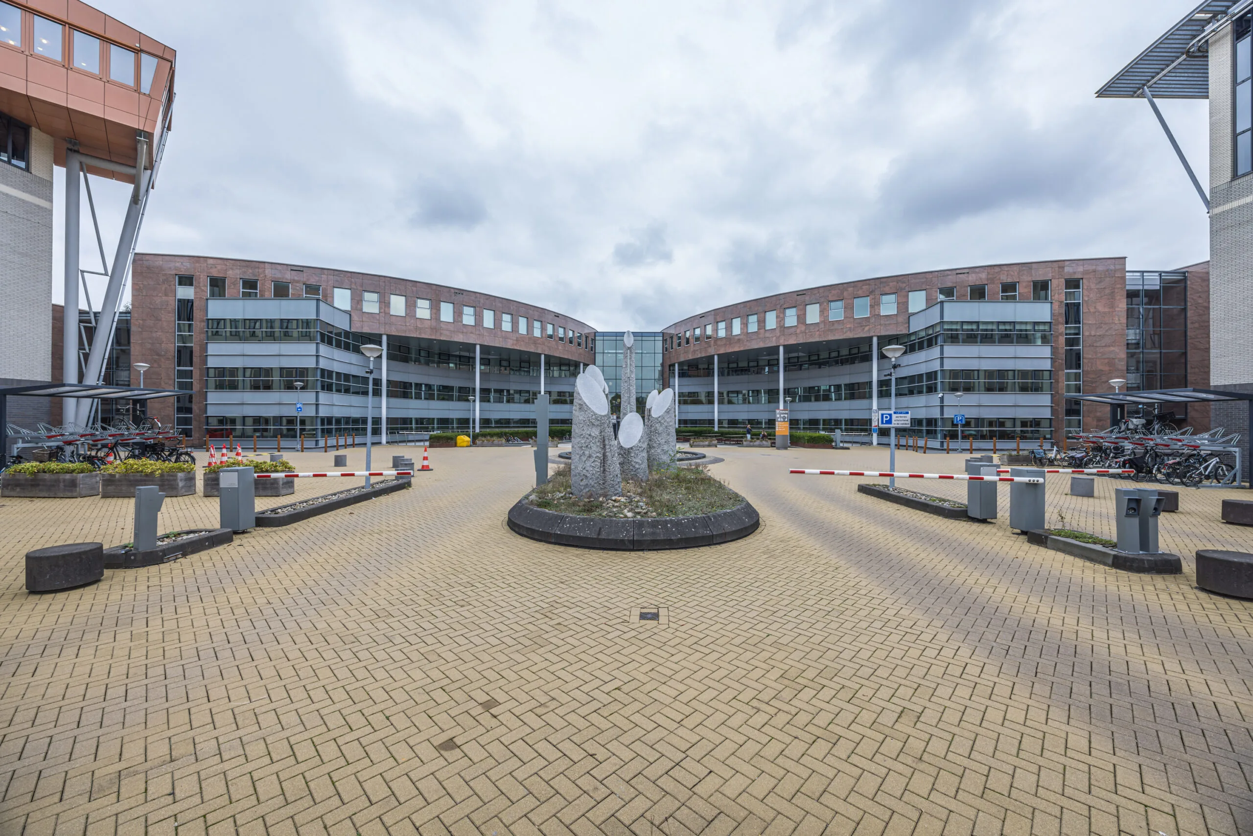 Modern office building of Olympia viewed from the entrance courtyard with a circular stone sculpture in the center.