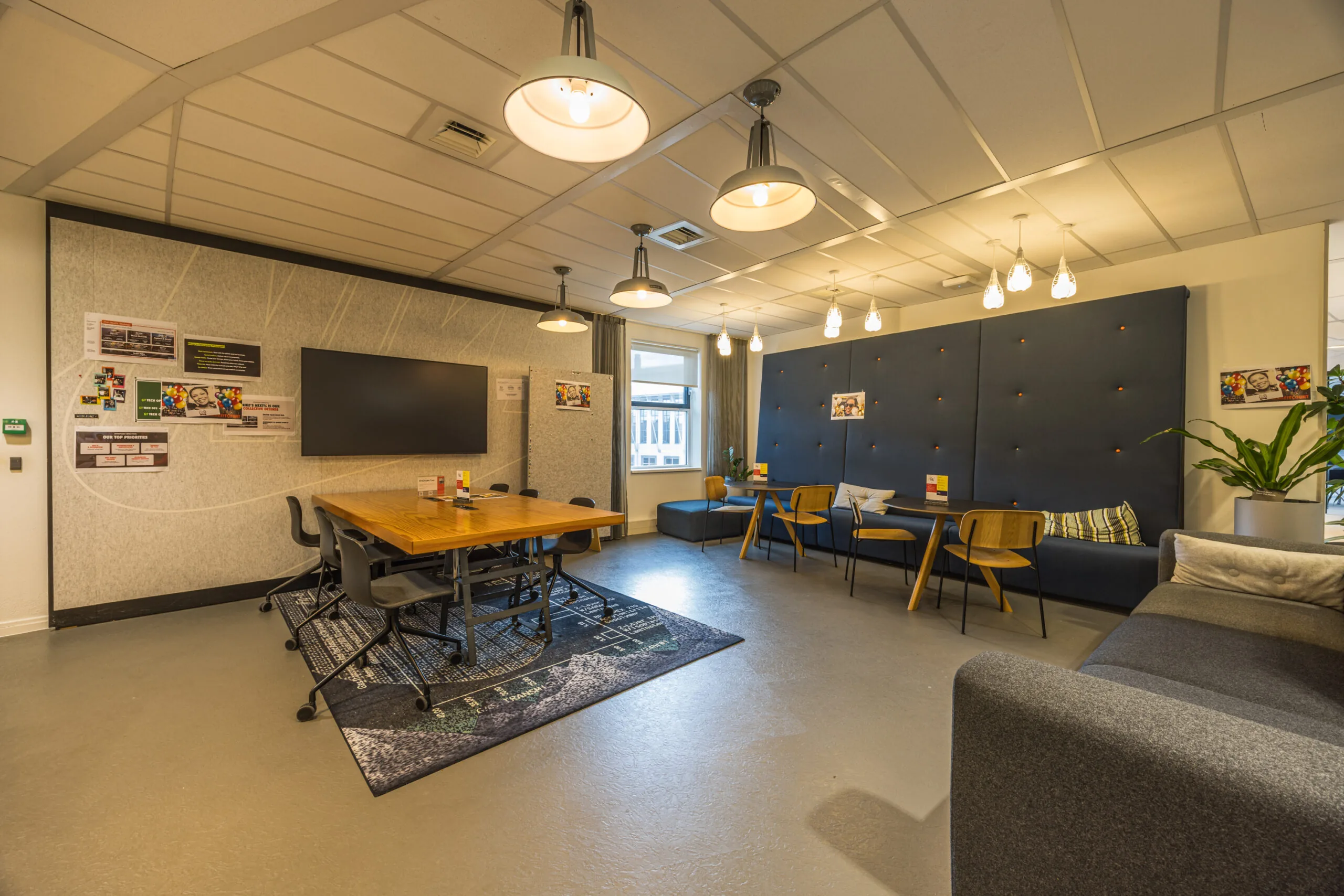 Modern office lounge area with a meeting table, cozy seating, and warm ceiling lights at Olympia.