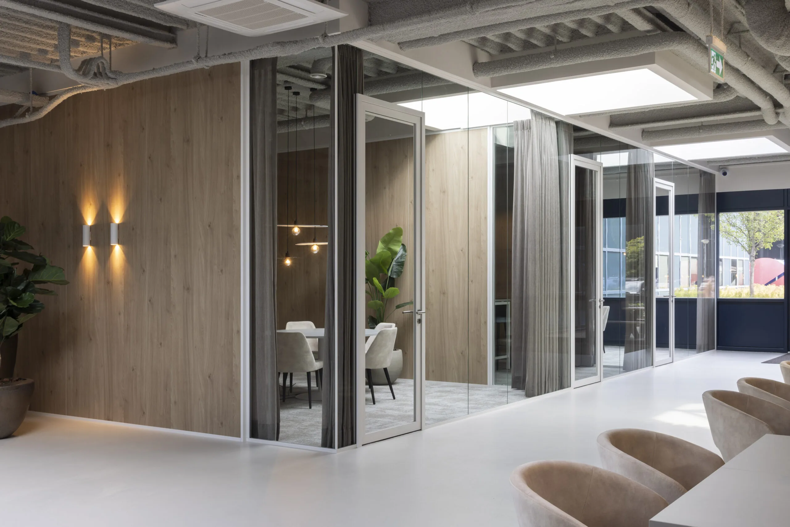 Modern office interior with glass-walled meeting rooms, wood paneling, and contemporary furnishings at Essebaan.