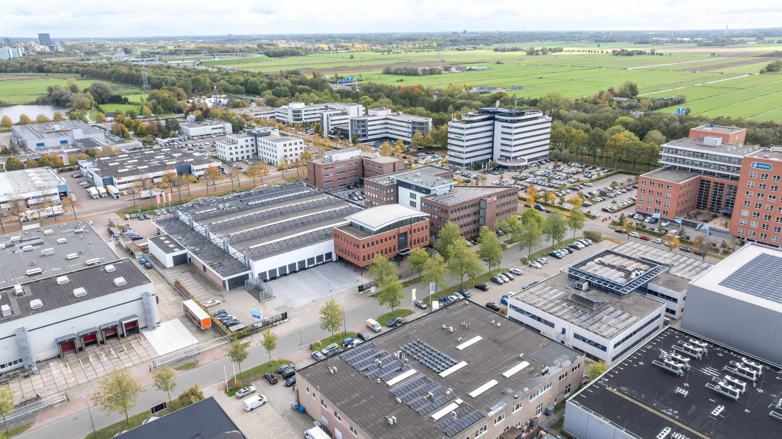 Aerial view of the Veldzigt business park featuring office buildings, warehouses, and surrounding green fields.