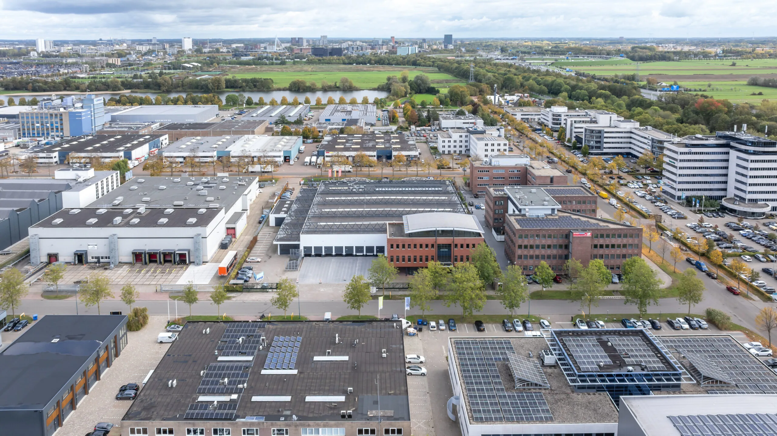 Aerial view of the Veldzicht business park with industrial buildings, offices, and solar panels in a green urban setting.