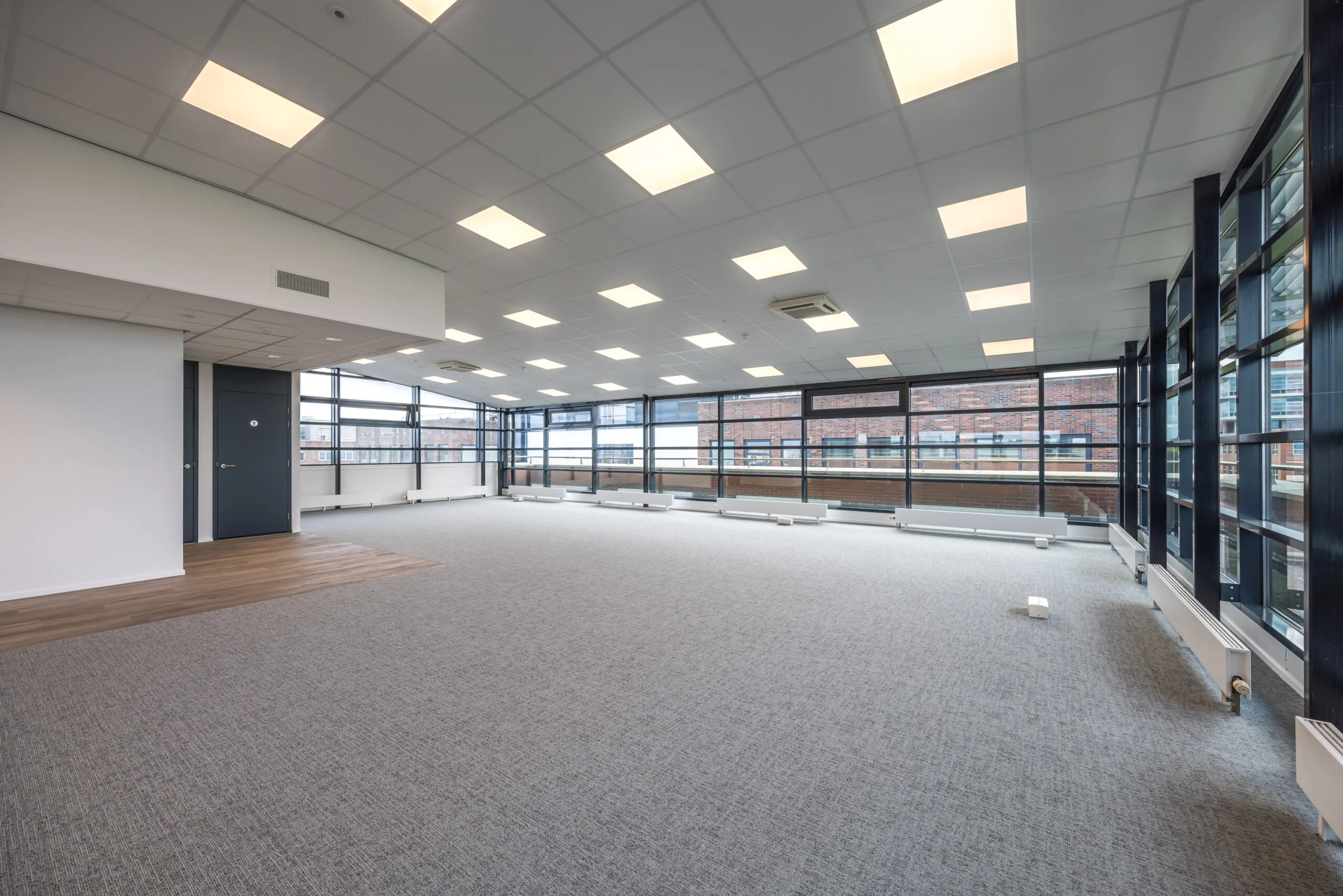 Spacious and modern empty office space at Veldzigt with large windows and ceiling lights.