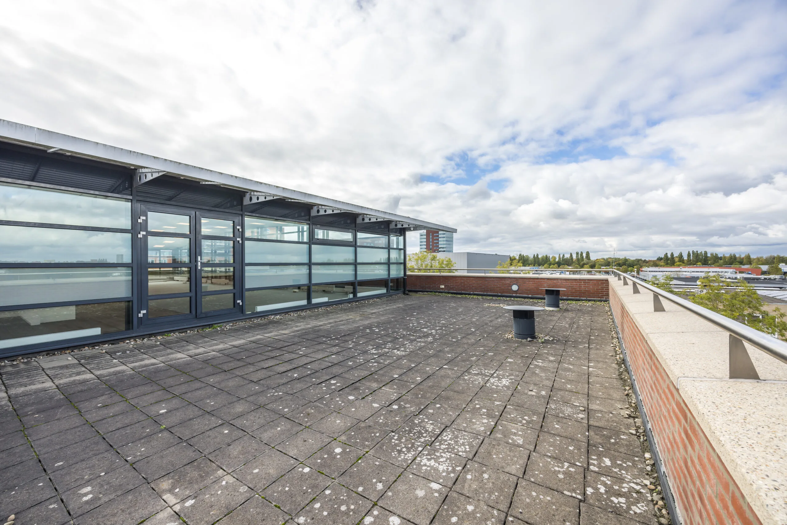 Spacious rooftop terrace with tiled flooring and modern glass facade at Veldzigt.