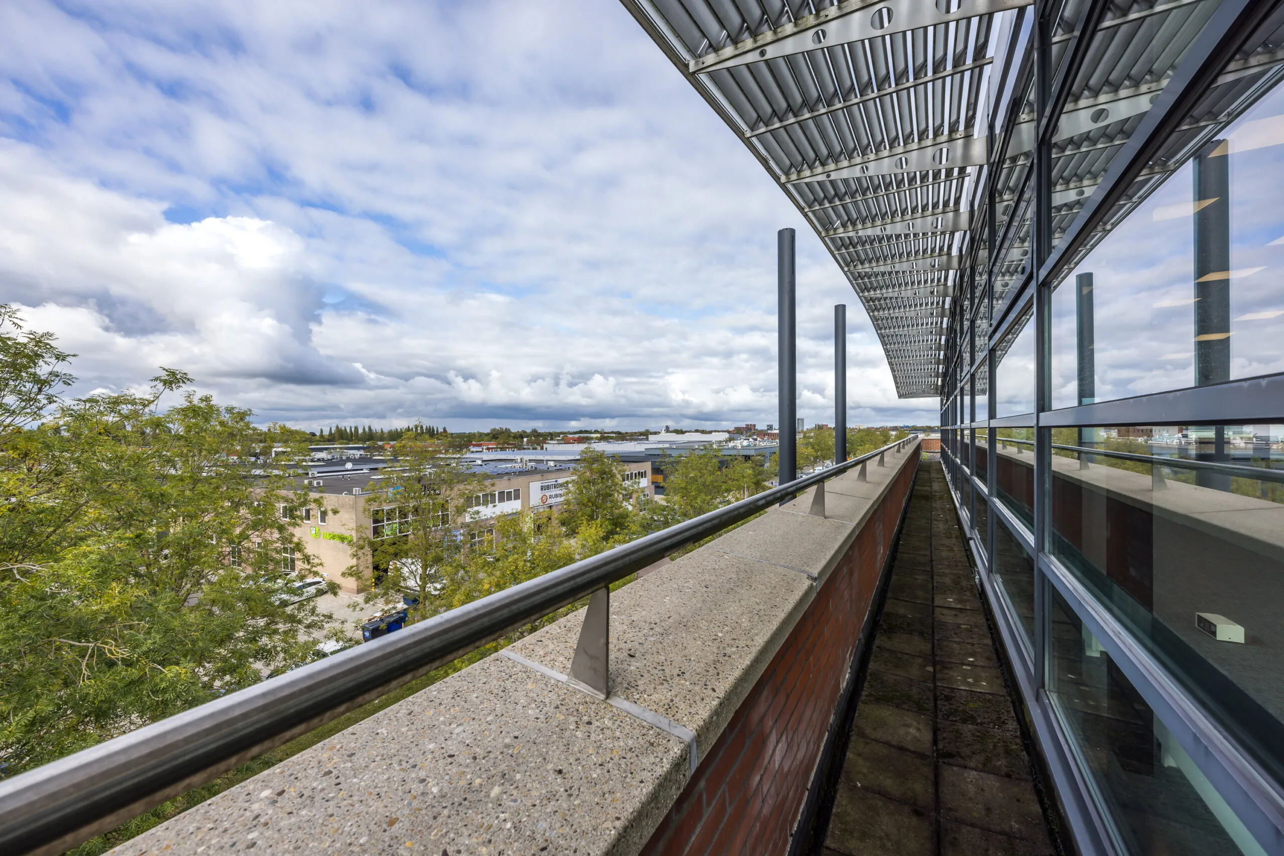 View from the upper terrace of the Veldzigt building overlooking an industrial area and a partly cloudy sky.