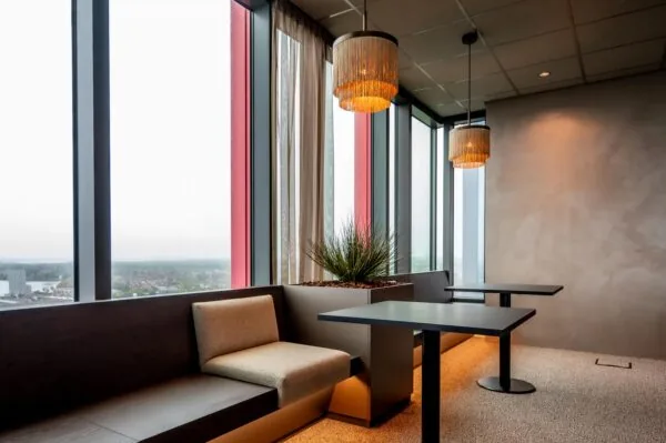 Modern seating area with large windows, pendant lights, and a view over P.J. Oudweg in Almere.