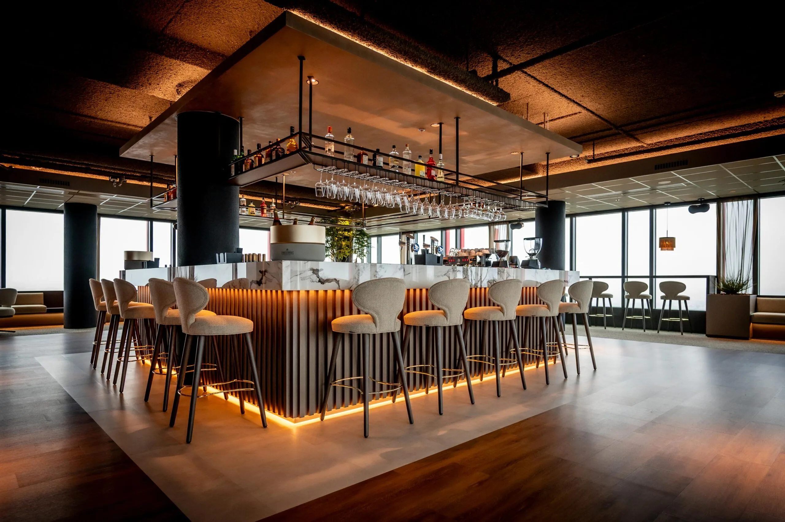 Modern bar interior with high stools, marble counter, and warm ambient lighting at P.J. Oudweg.