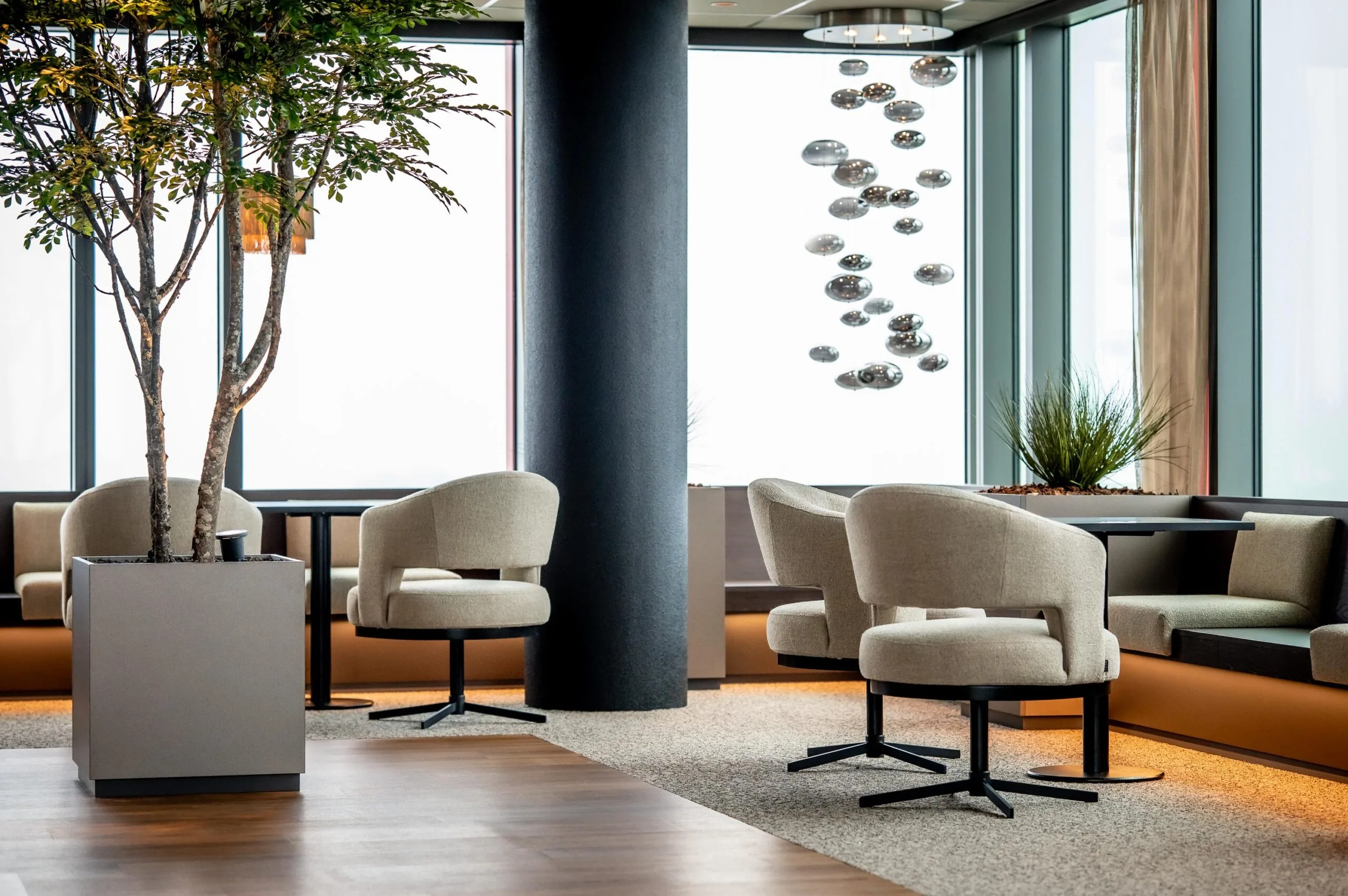 Modern lounge area at P.J. Oudweg with neutral-toned seating, large windows, and contemporary decor.