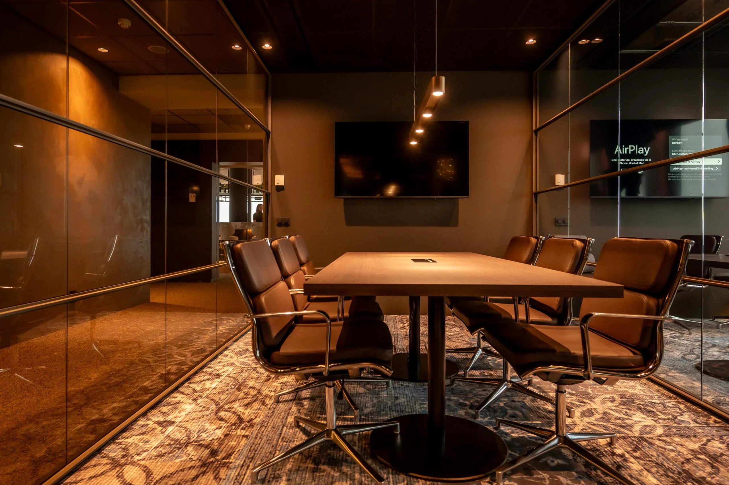 Modern conference room on P.J. Oudweg with leather chairs, a large screen, and warm ambient lighting.