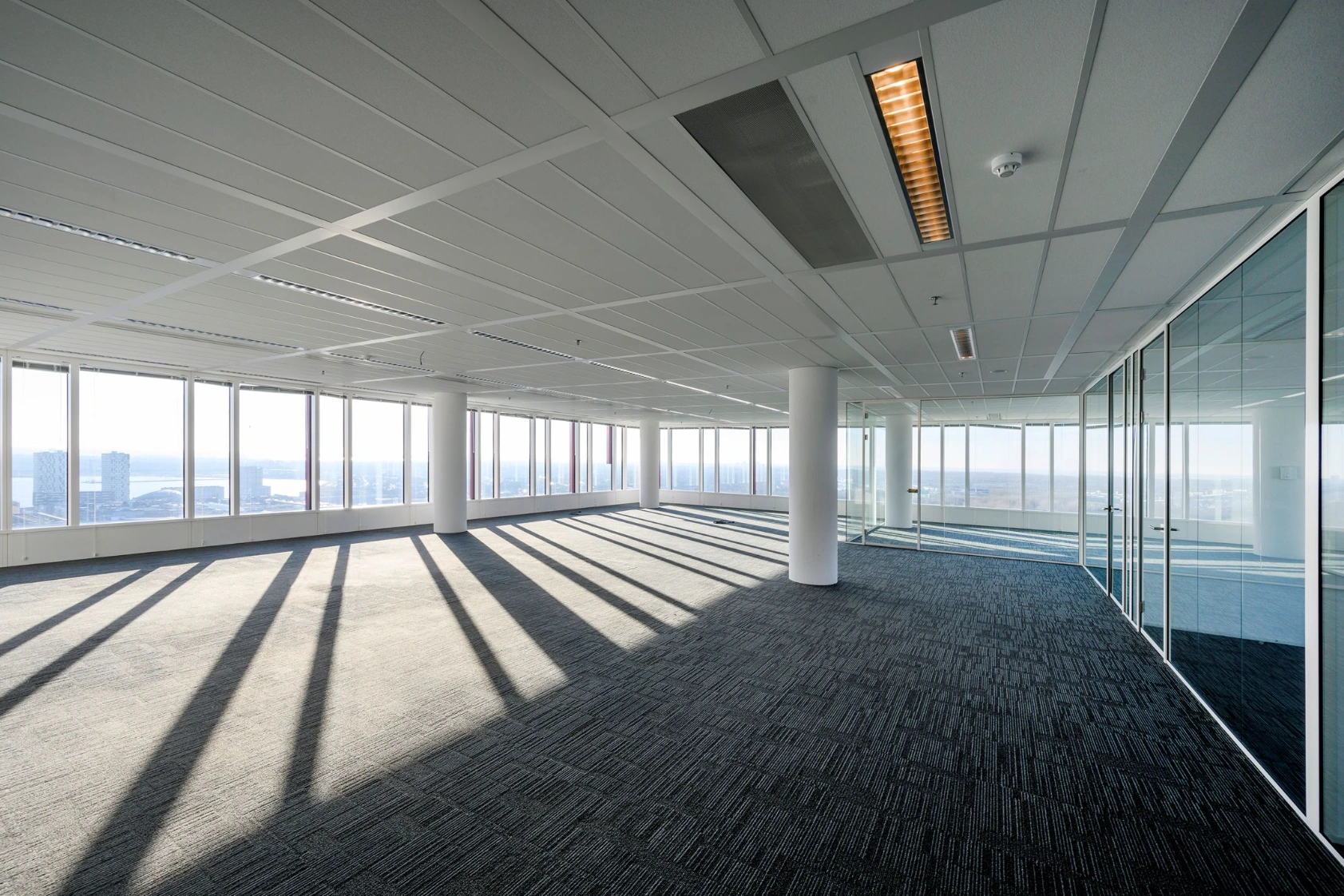 Bright empty office space with large windows, glass walls, and city views on P.J. Oudweg.