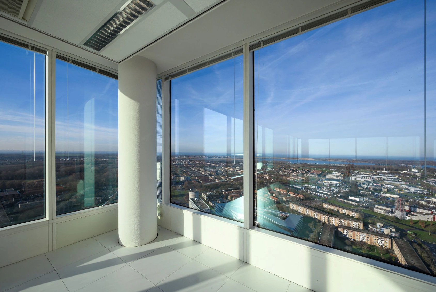 Corner of a modern office building on P.J. Oudweg with large glass windows offering a panoramic view over Almere and the surrounding landscape.