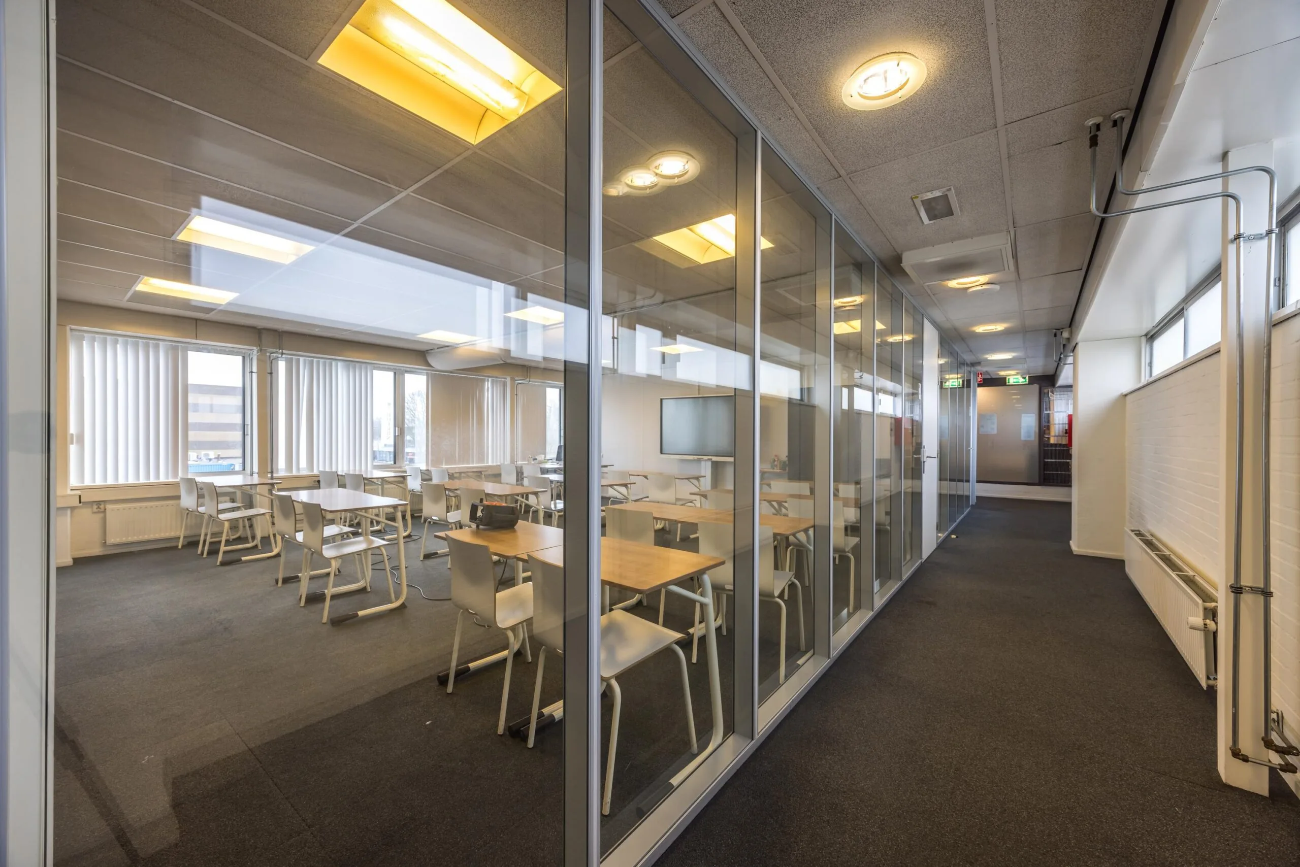 Modern classroom with glass walls and rows of white desks located on Aluminiumstraat.