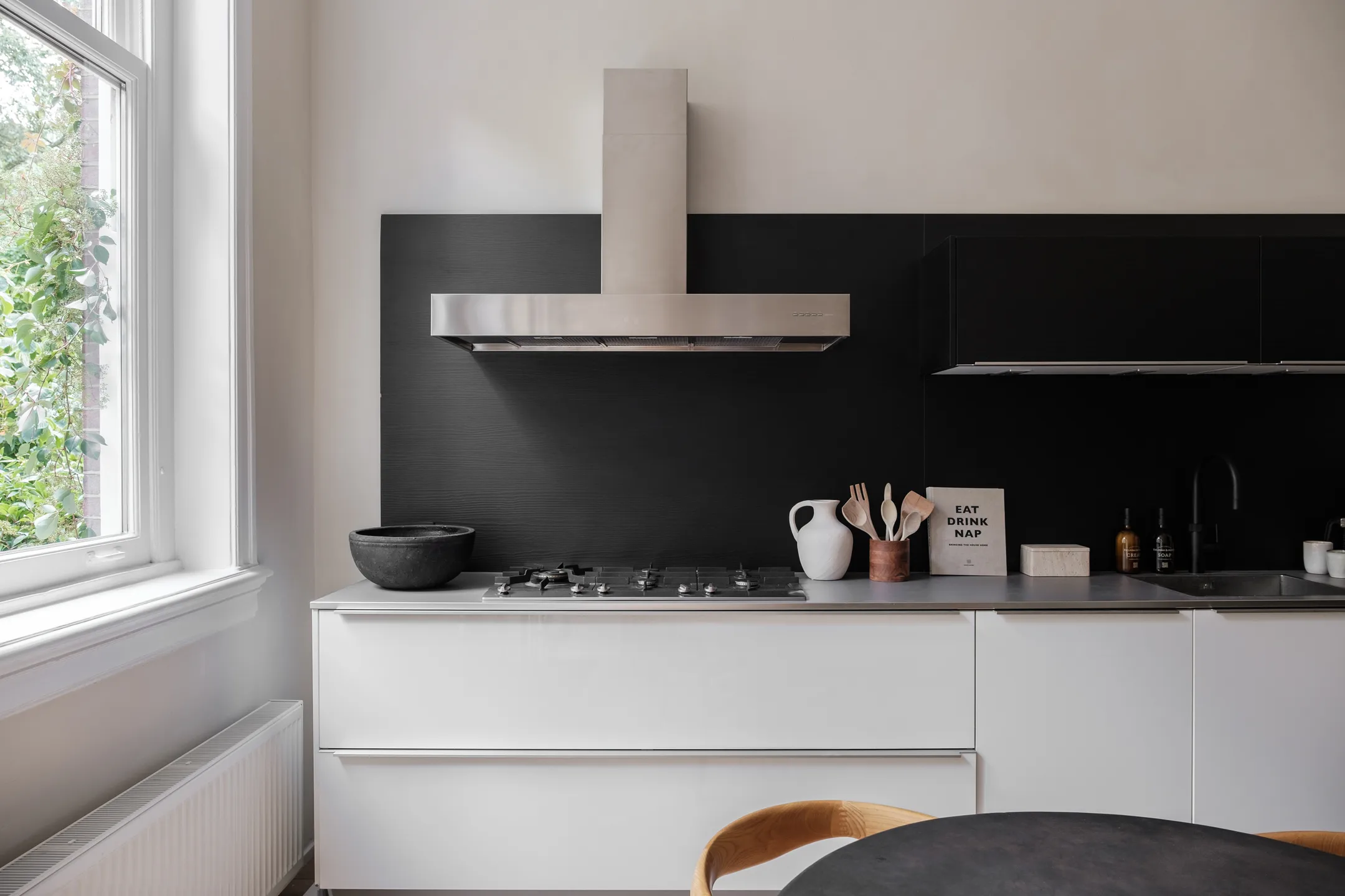 Moderne keuken met zwart-witte inrichting en roestvrijstalen afzuigkap.