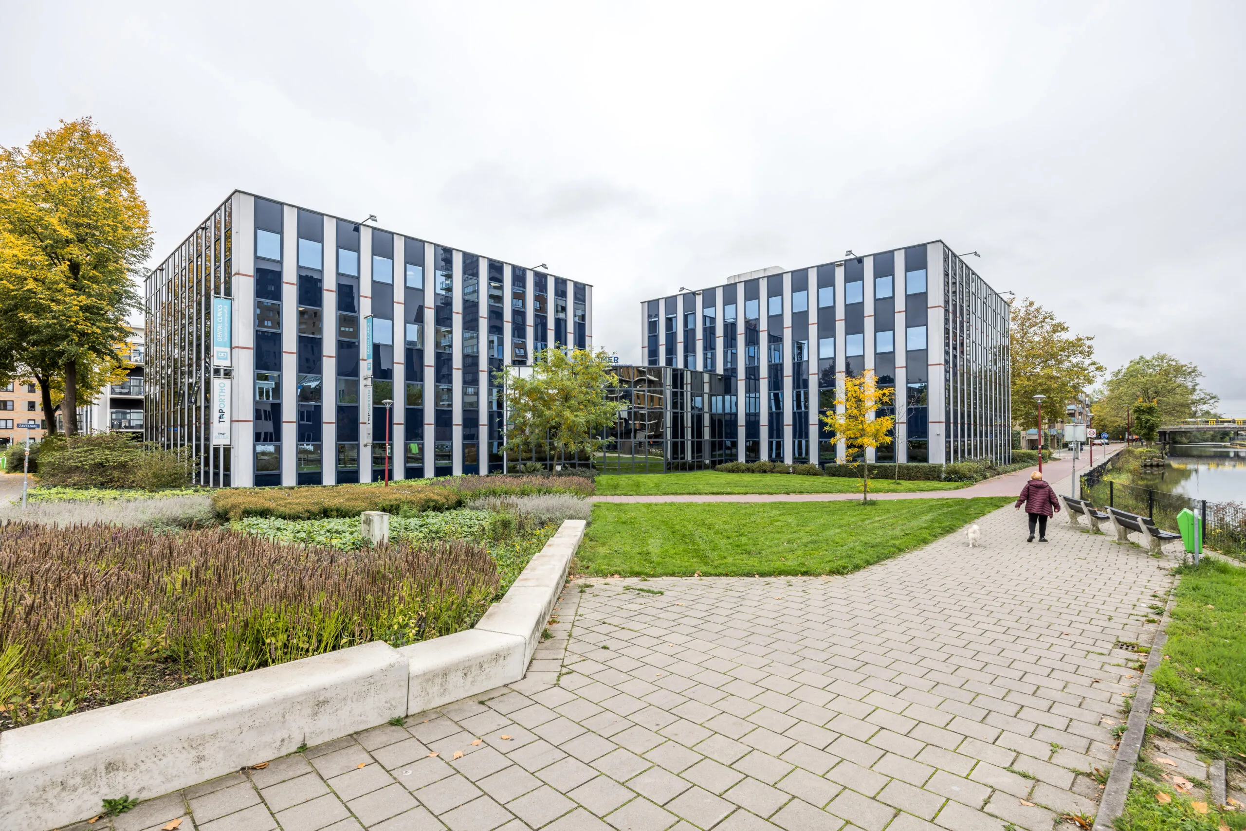 Modern office buildings on Krijtwal street in a landscaped urban setting next to a canal.