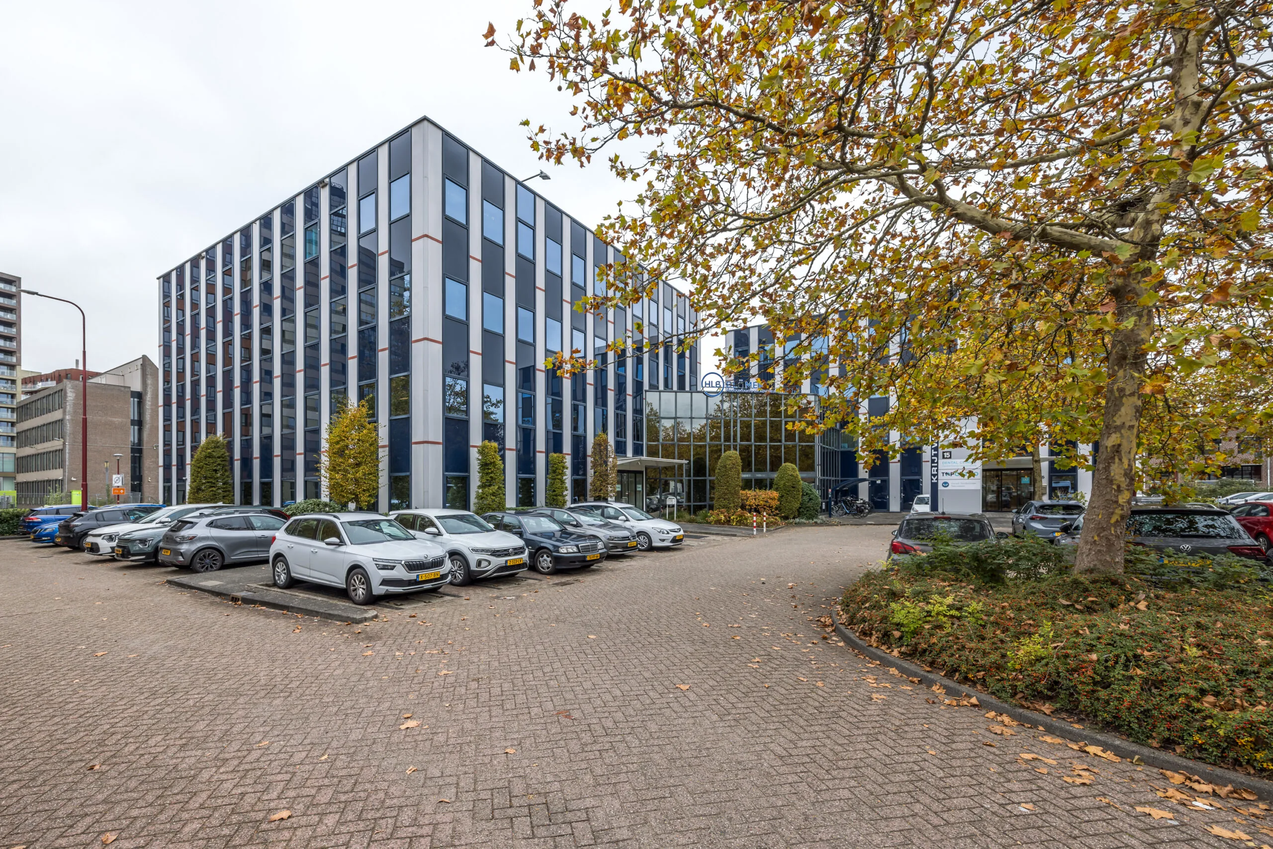 Modern office building on Krijtwal with a parking lot and autumn trees in front.