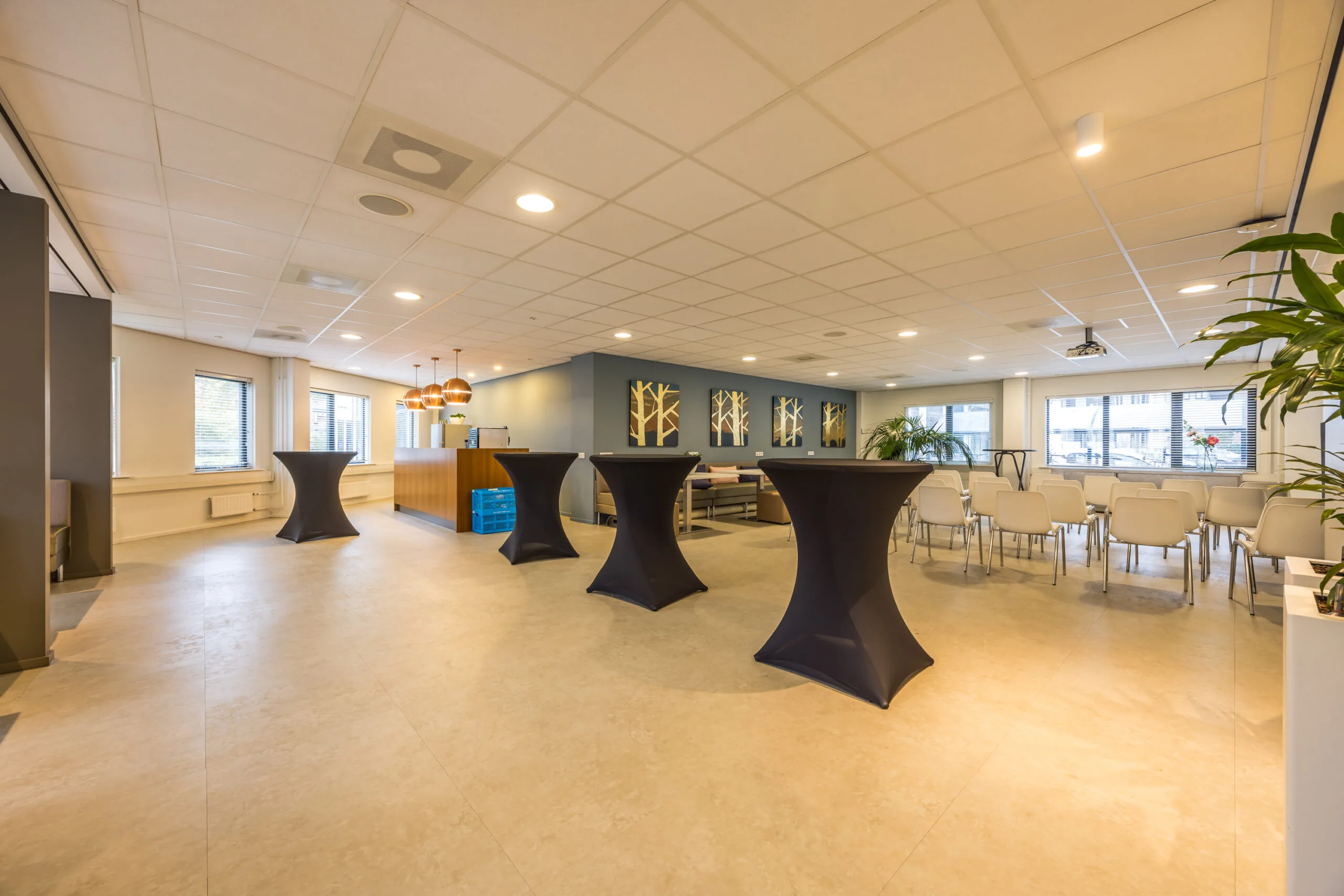 Modern reception and meeting area with high tables, white chairs, and large windows at Krijtwal 251.