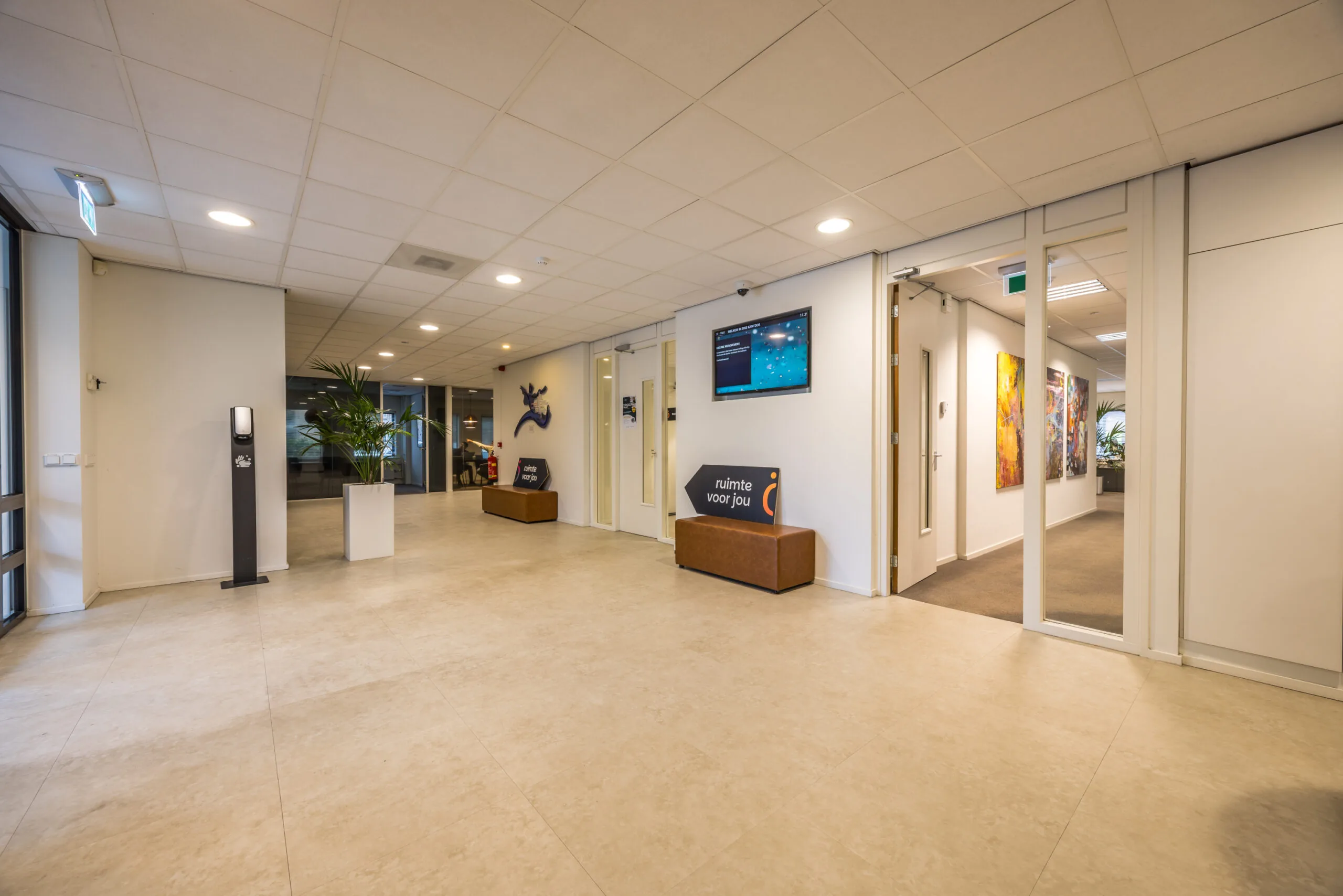 Modern office lobby at Krijtwal with seating, signage, and hallway displaying colorful artwork.