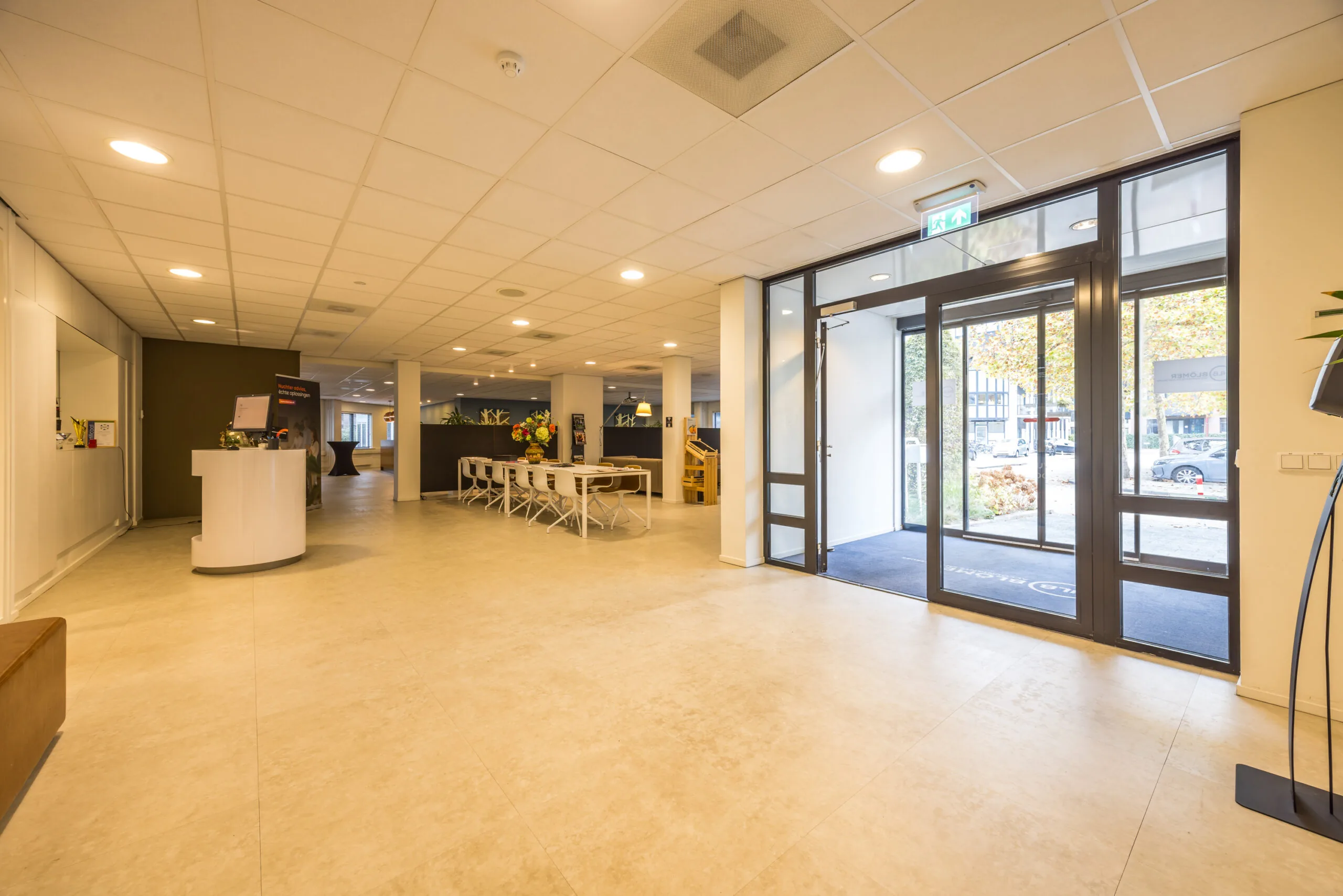 Bright and modern entrance hall of Krijtwal 20 with a reception desk, meeting area, and glass doors leading outside.