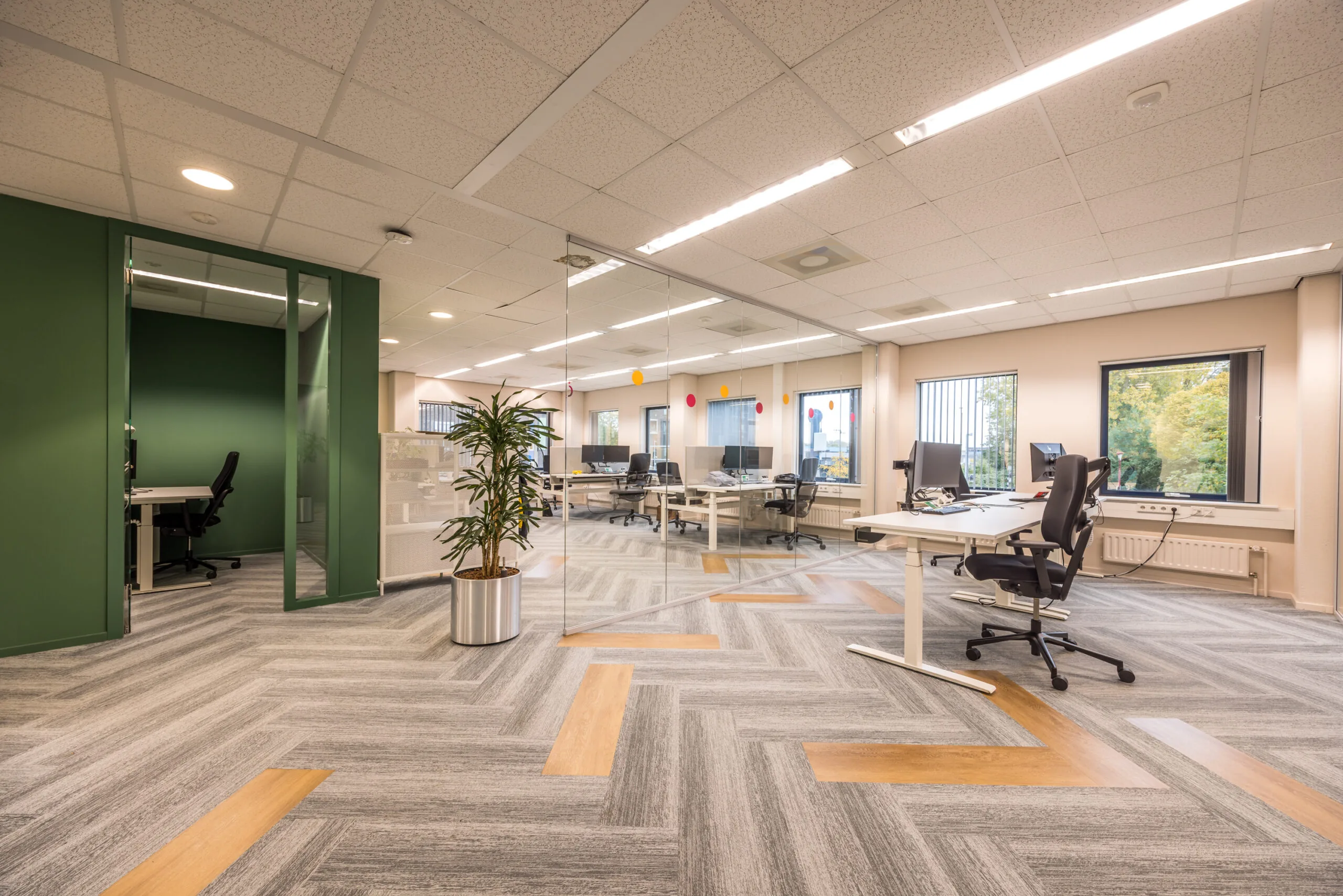Modern open office space on Krijtwal with glass walls, ergonomic chairs, and a patterned grey-and-wood floor.