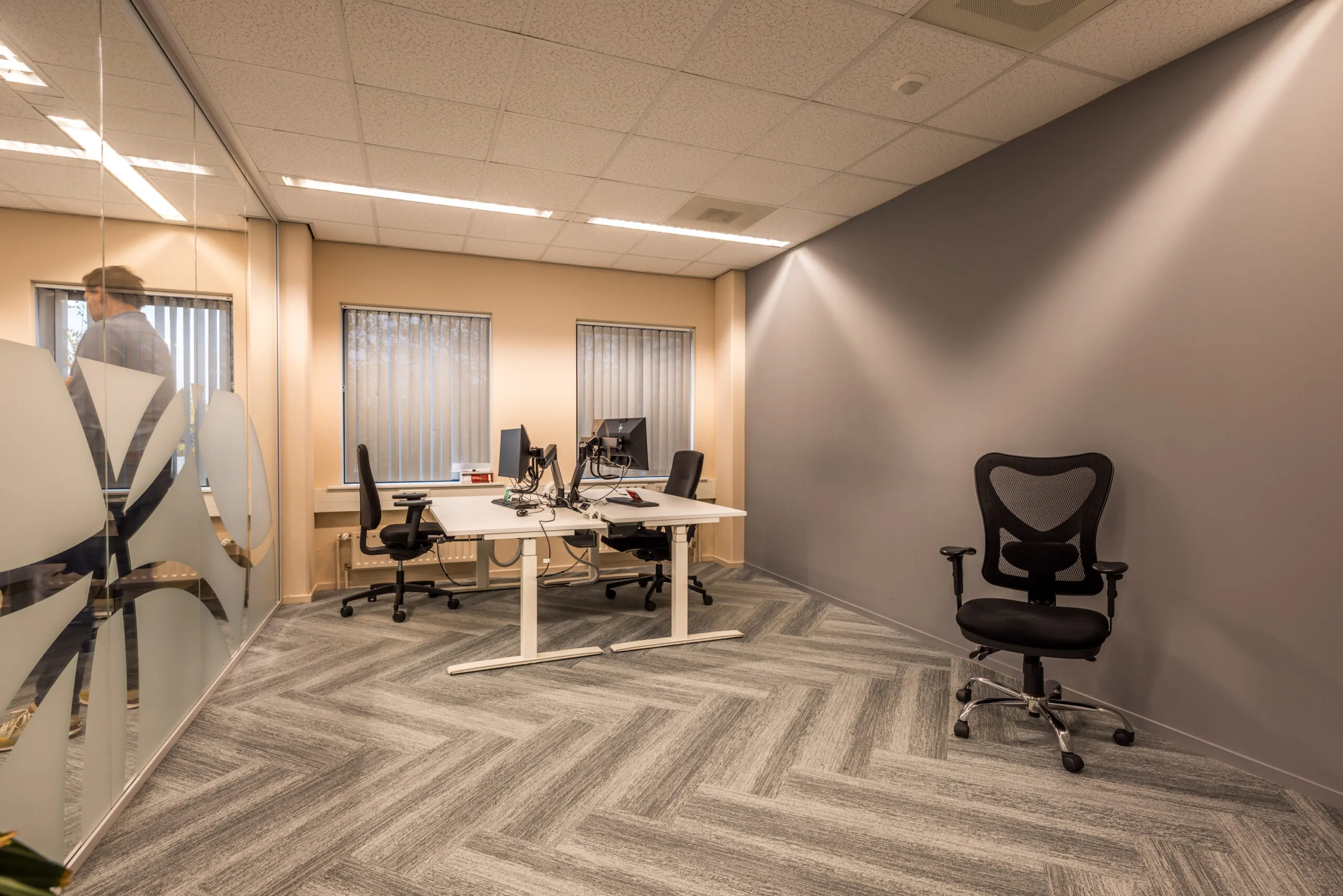 Modern office space with ergonomic chairs, computer desks, and frosted glass walls at Krijtwal.